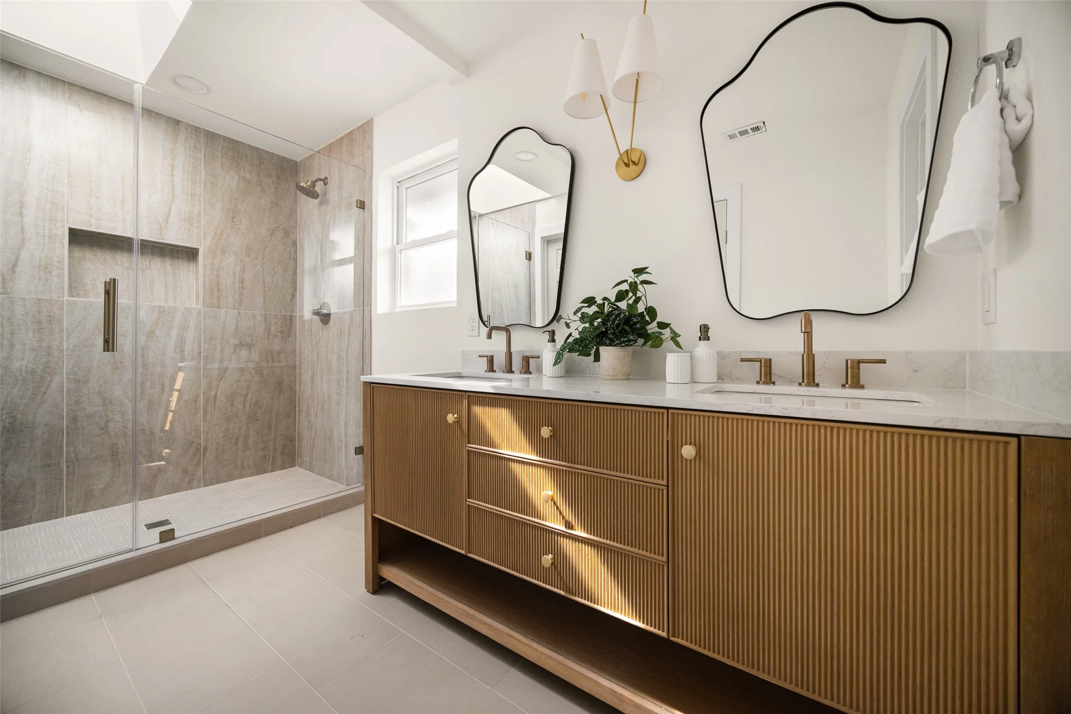 Spa-inspired primary bathroom featuring an expansive glass-enclosed shower with striking floor-to-ceiling tile, rich natural textures, and a seamless design that creates a serene, resort-like retreat.