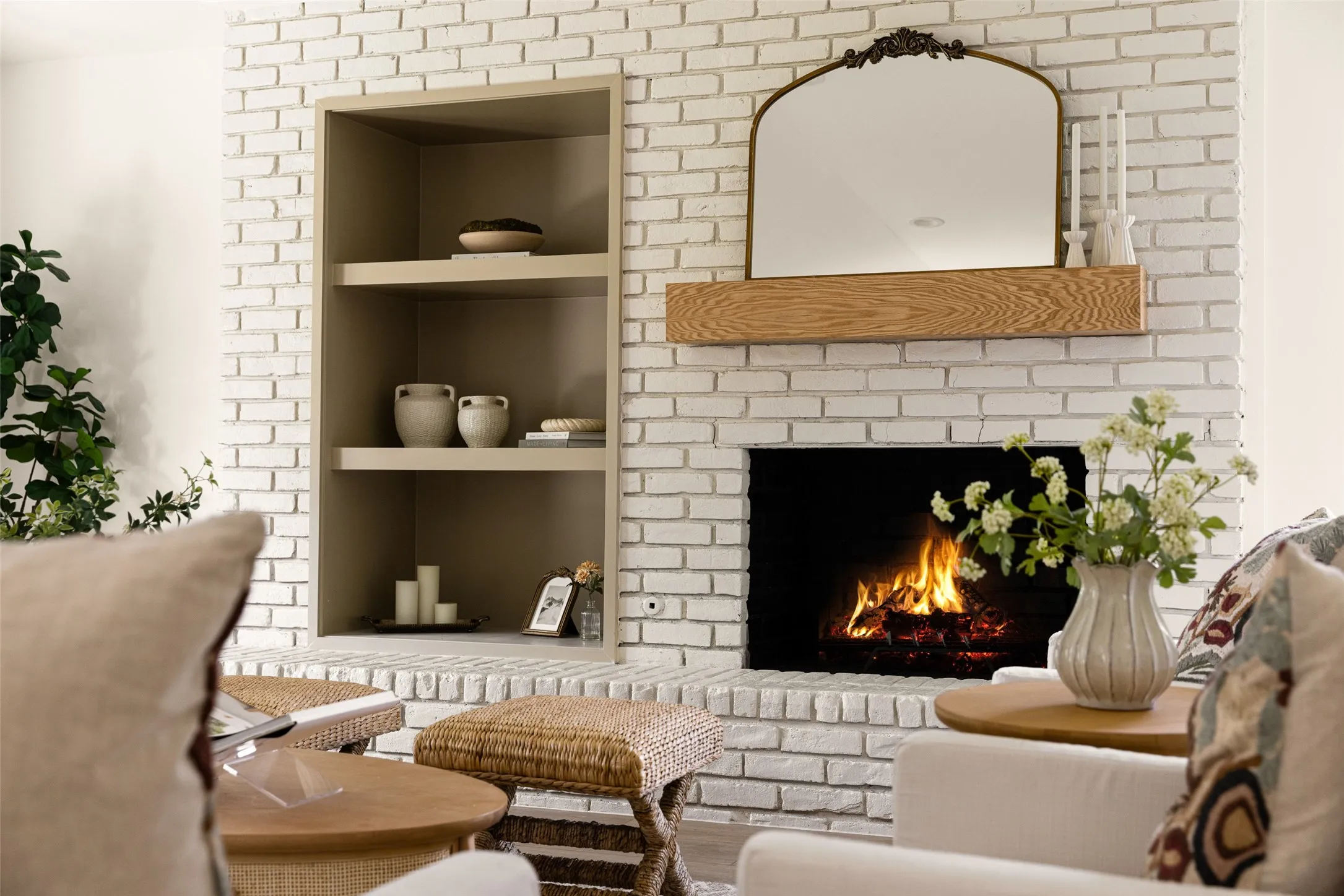 Striking refinished white brick fireplace featuring a natural wood mantel and built-in shelving, creating an elegant focal point with timeless character.