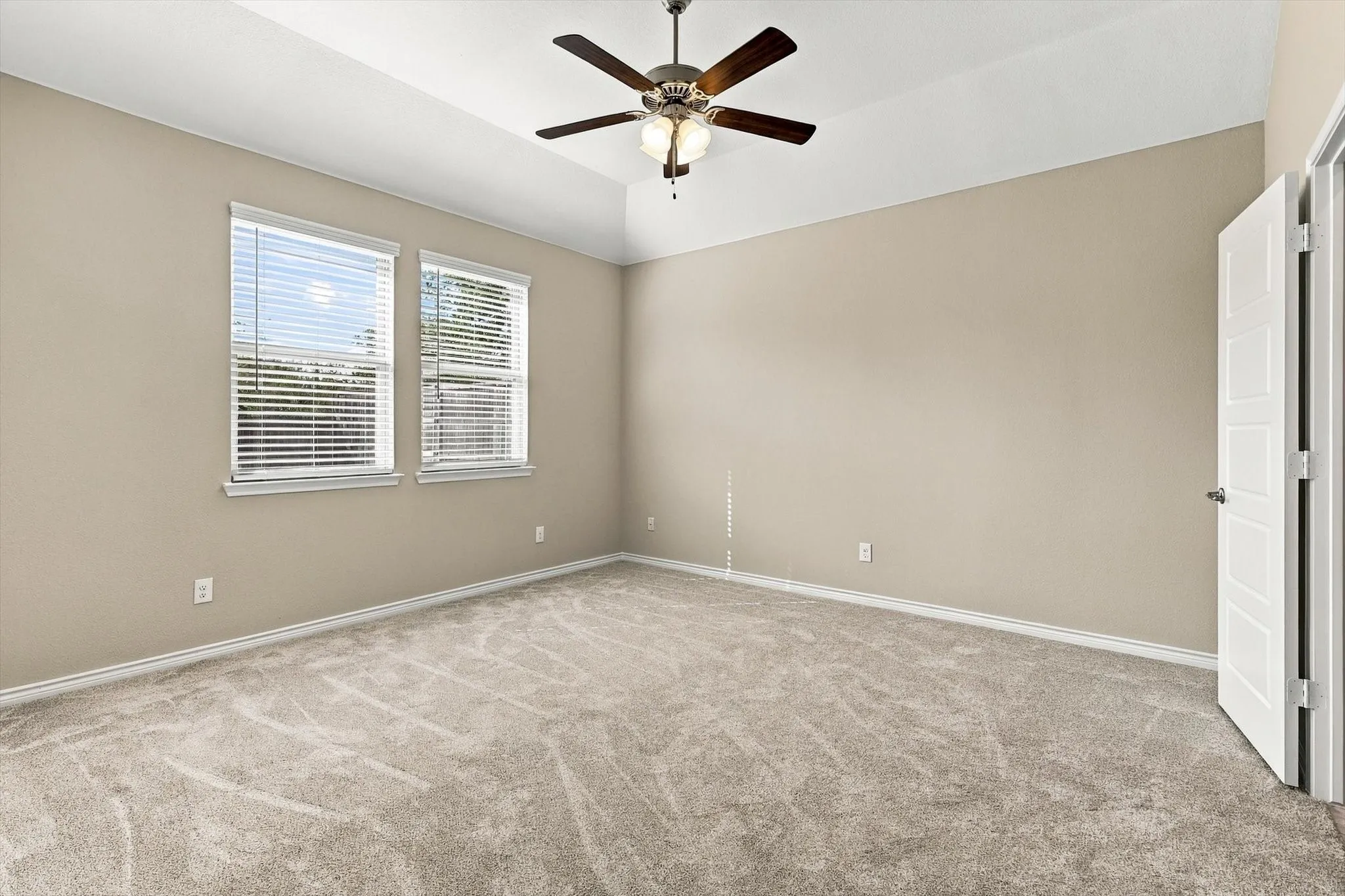 Primary bedroom with ceiling fan, fresh paint and new carpet.  View is to the backyard.