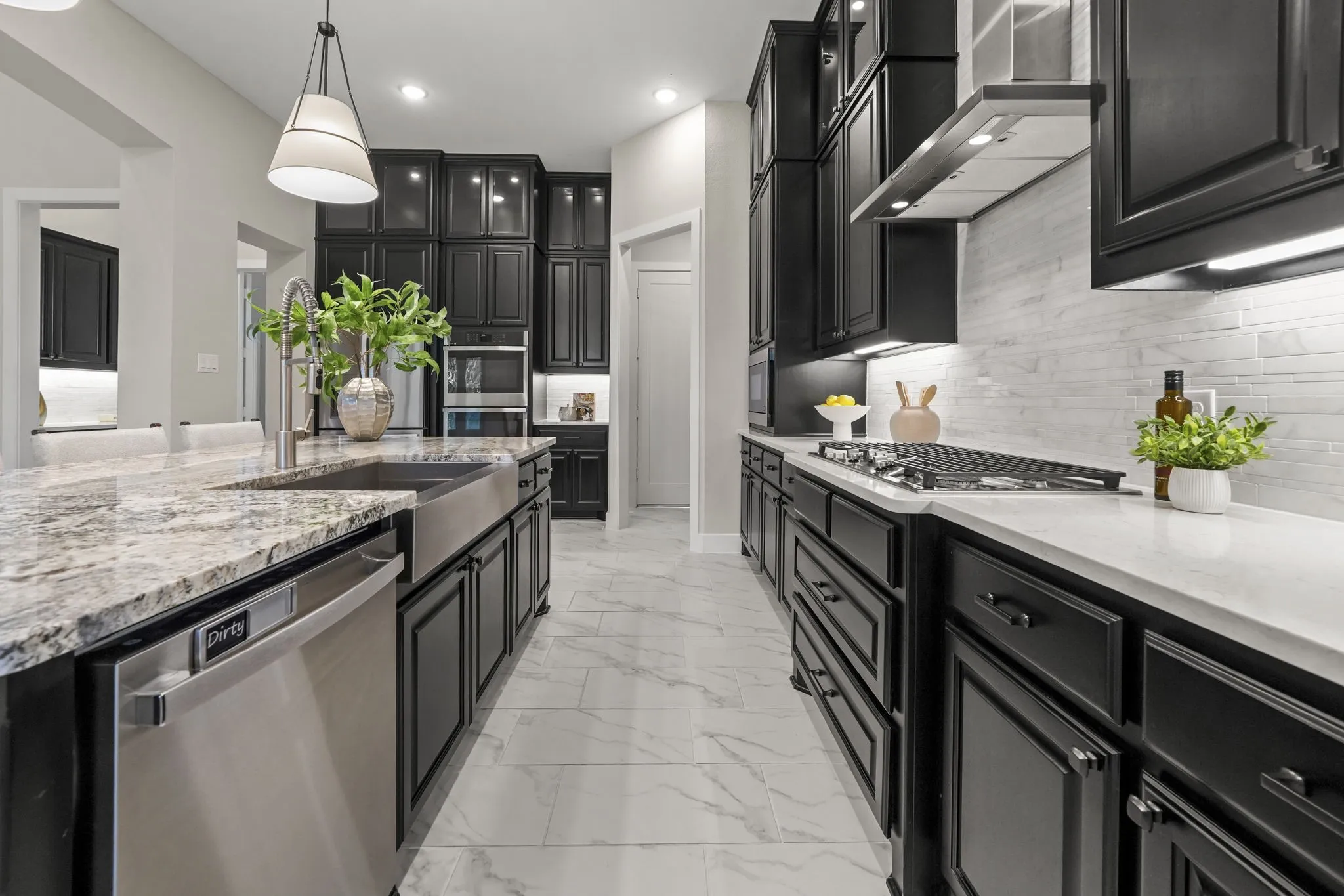 Kitchen featuring dark custom cabinetry, stone countertops, farmhouse-style sink, integrated gas cooktop, and tile flooring