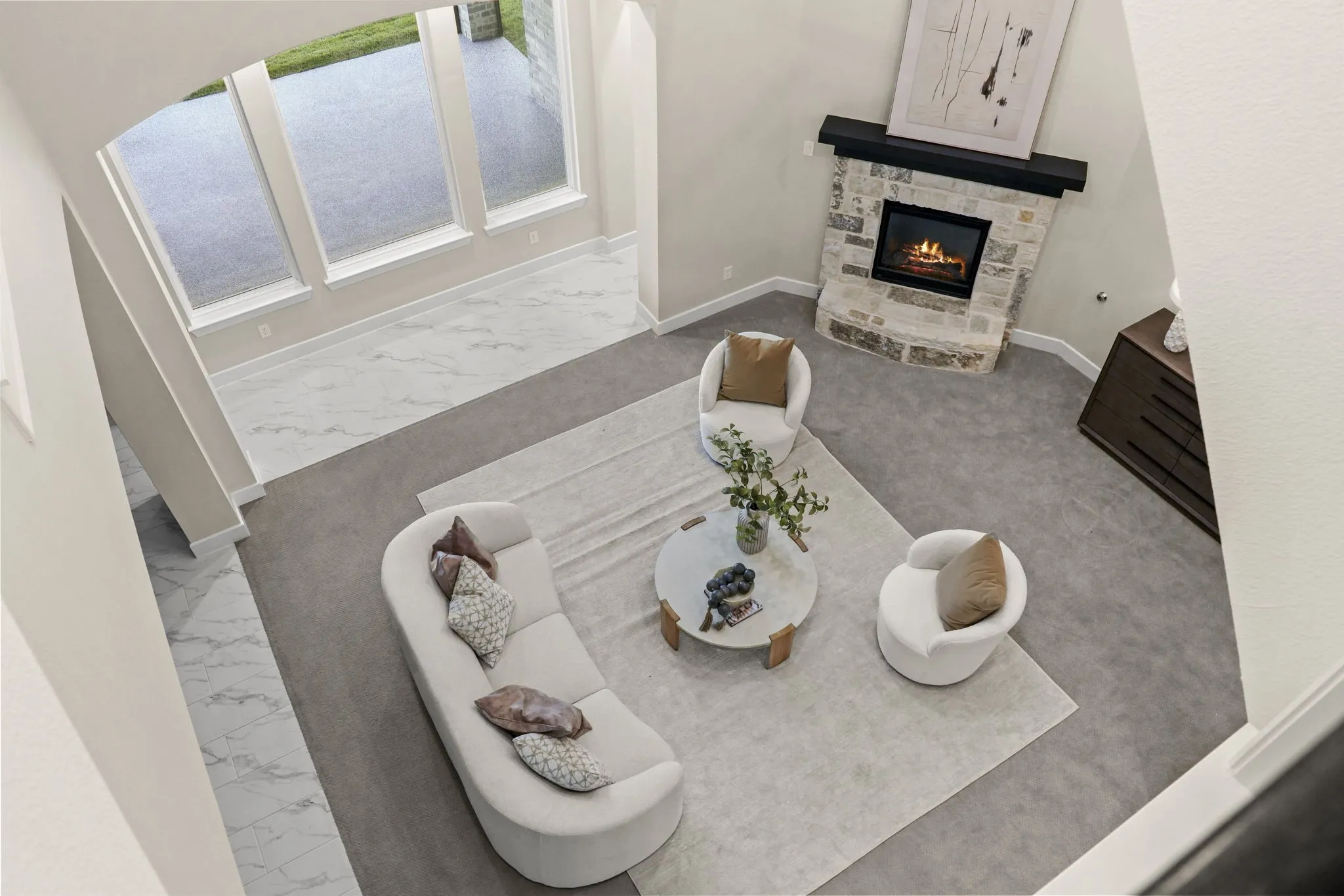 Two-story living area featuring floor-to-ceiling windows, natural stone fireplace with a floating mantle, and a combination of carpet and large-format tile flooring
