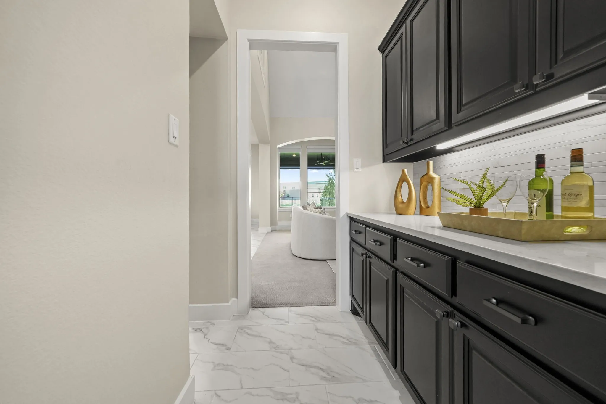 Built-in cabinetry with matte black finish, light-toned stone-look countertop, horizontal tile backsplash, and light-toned tile flooring