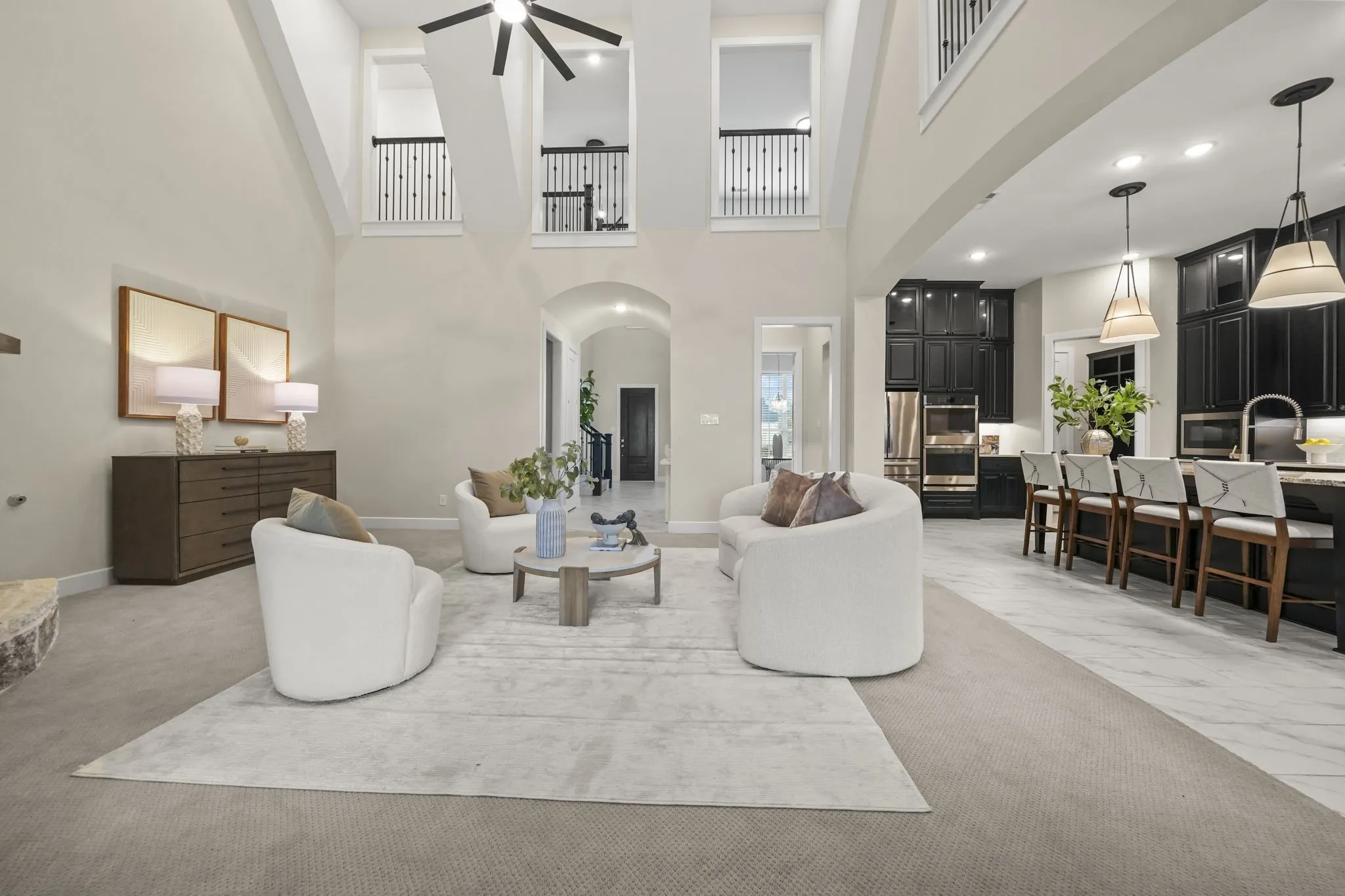 Vaulted ceilings with architectural balcony overlook, tile flooring, recessed lighting, and custom dark cabinetry with pendant light fixtures