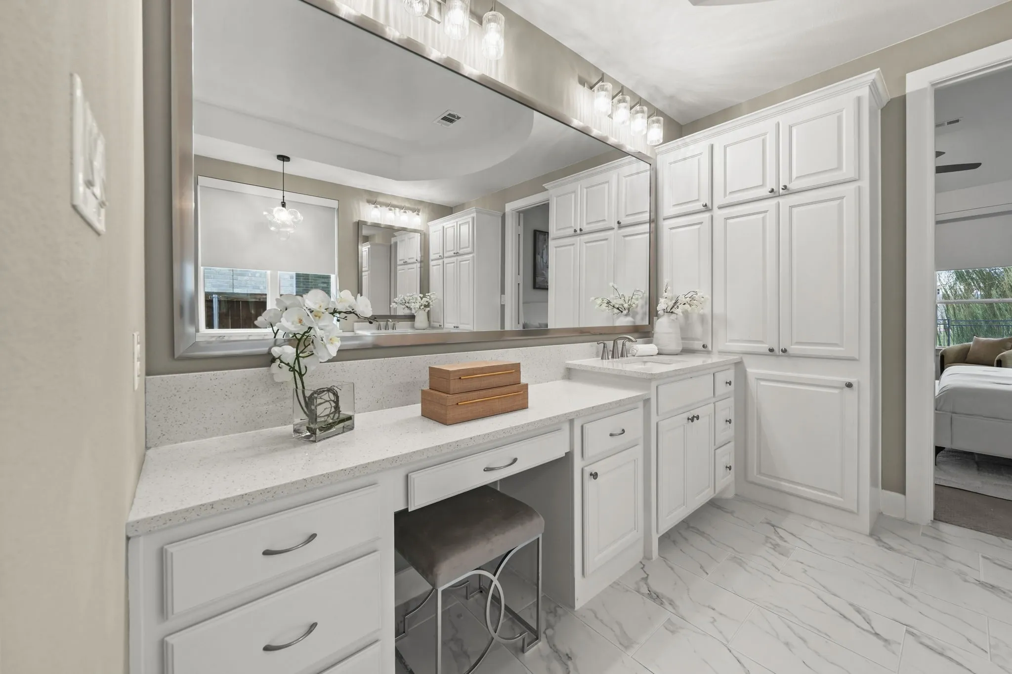 Vanity featuring a full-width mirror, white cabinetry, quartz countertop, and stone-finish tile flooring
