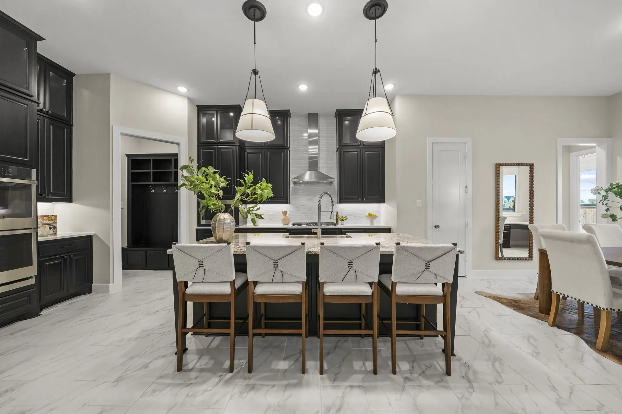 Kitchen featuring custom cabinetry, stone-surface central island, stainless steel double wall oven, metal range hood, and tile flooring