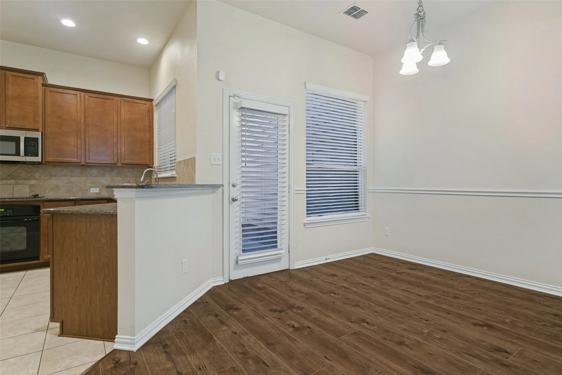 Wood-finish flooring, chair rail molding, recessed lighting, wood cabinetry, and solid surface countertops