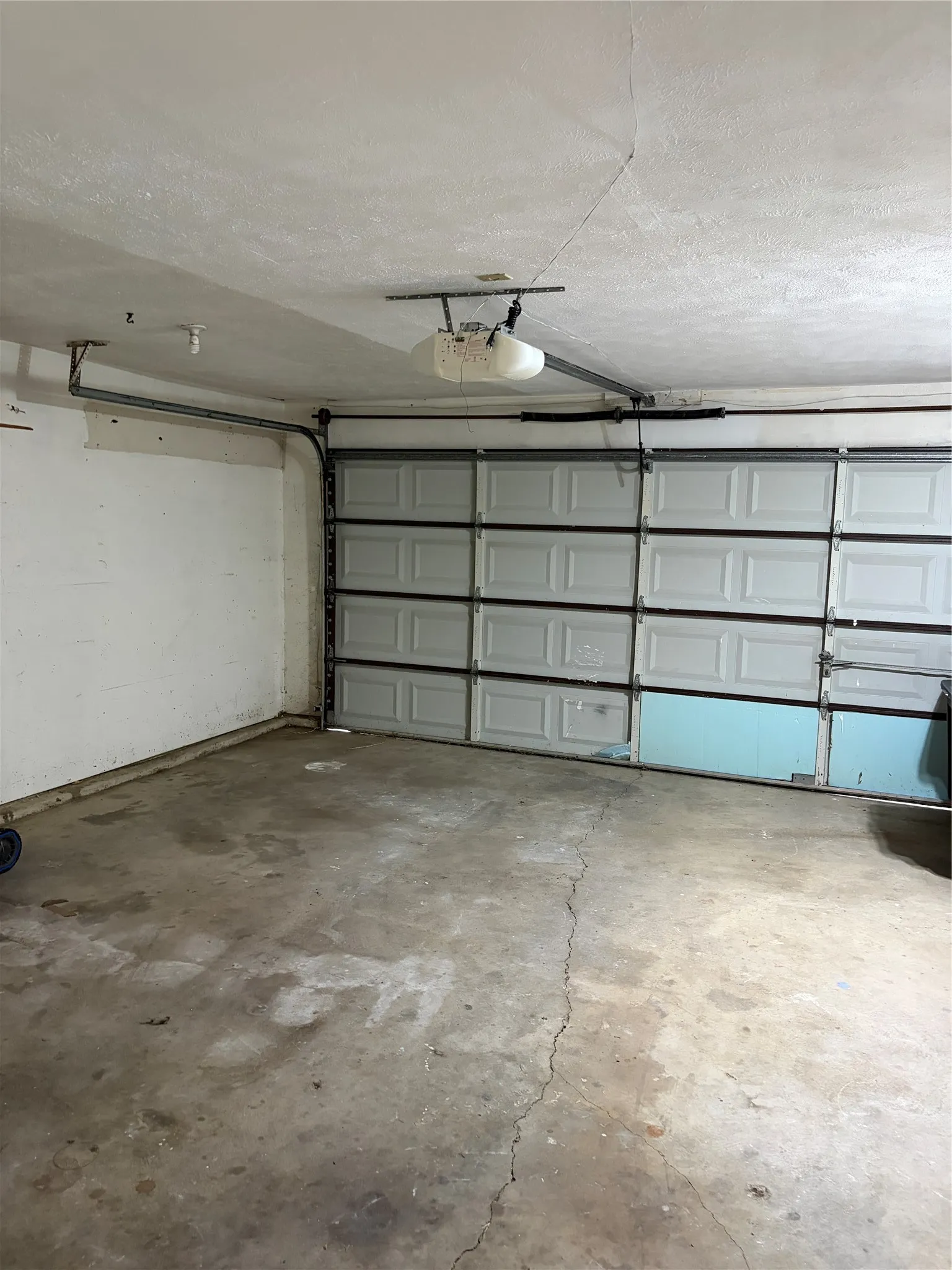 Enclosed garage space featuring a multi-panel overhead door and integrated electric door opener