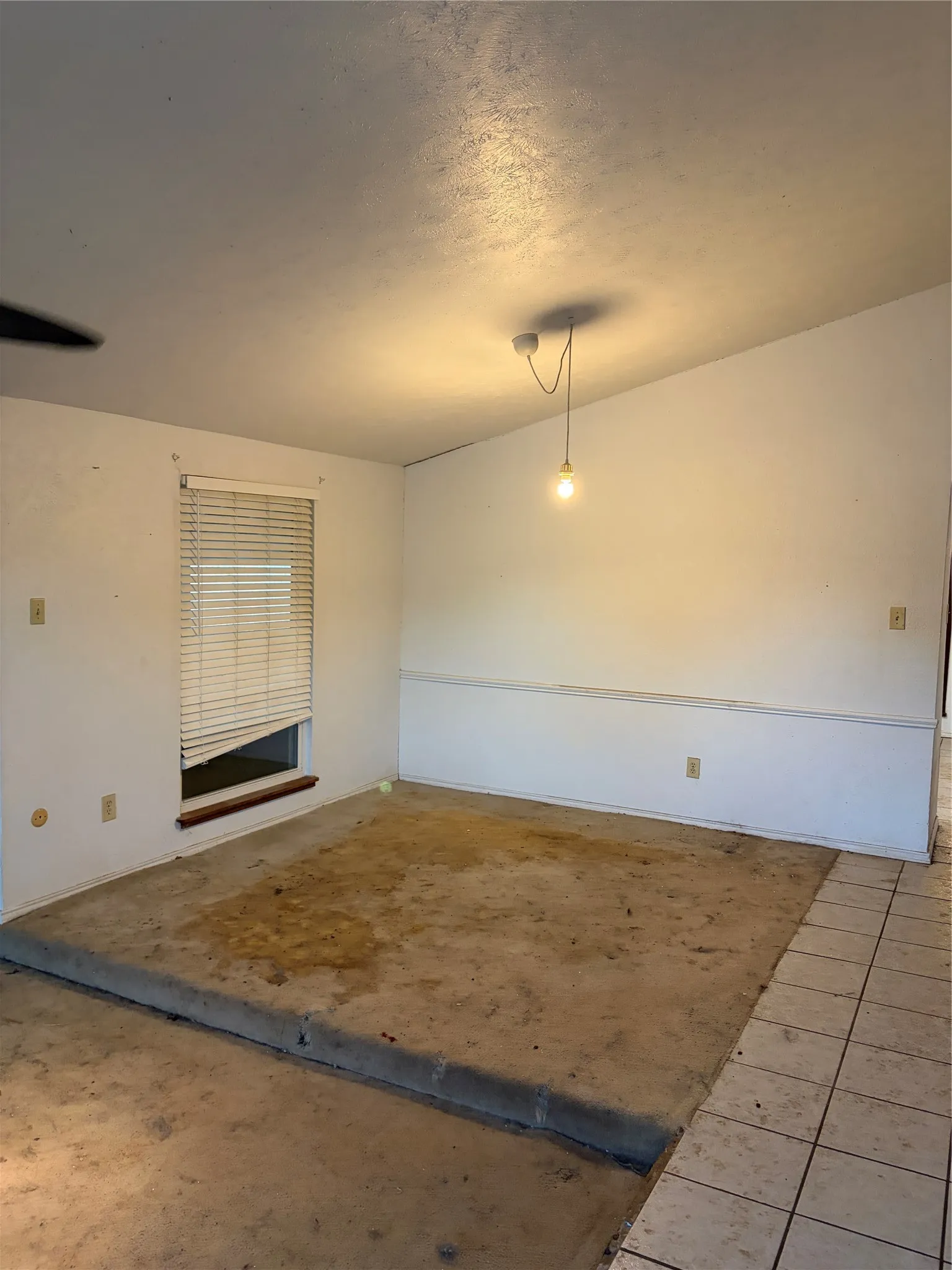 Sloped ceiling, raised platform flooring, window with built-in blinds, and tile flooring