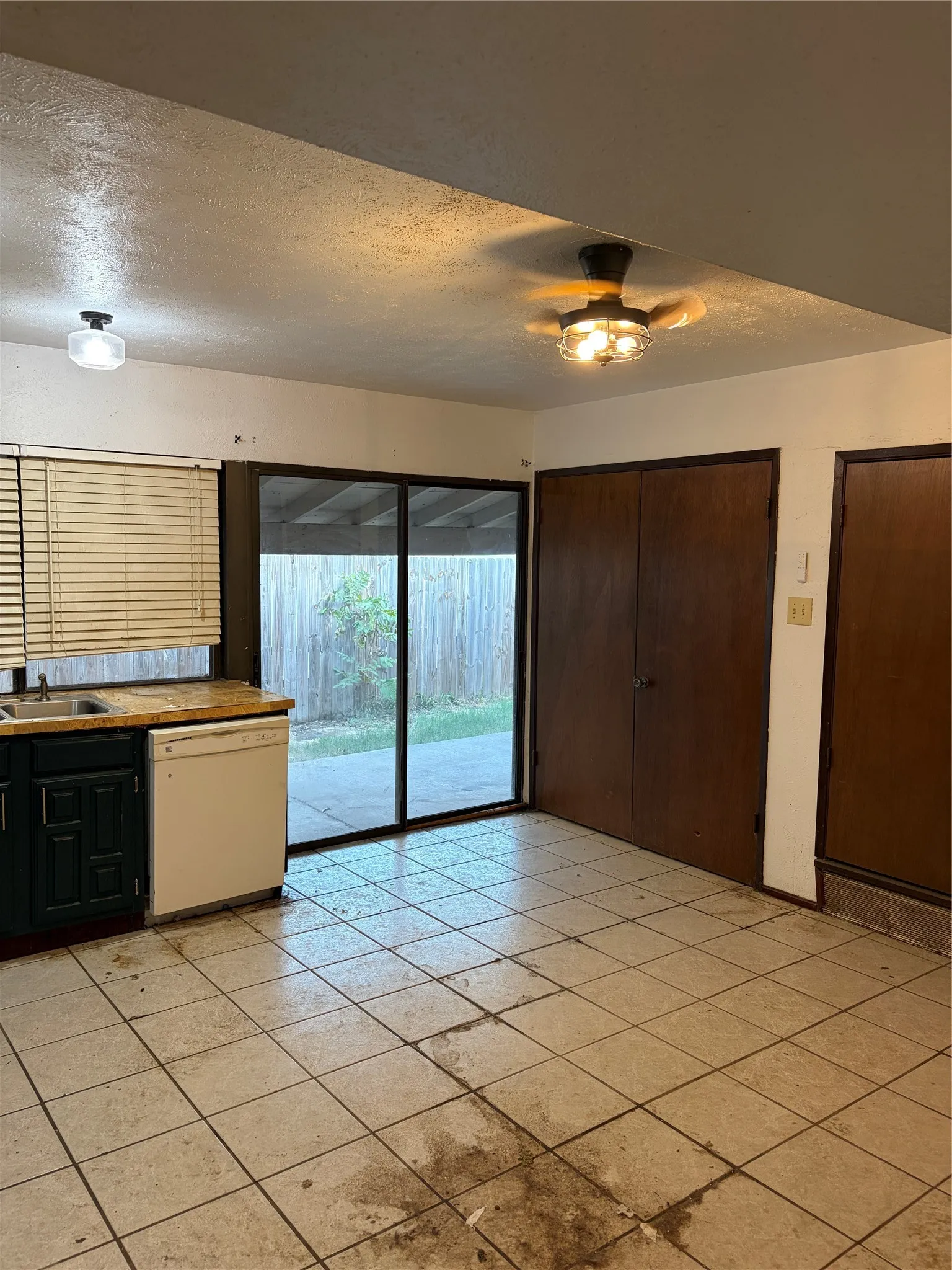 Kitchen featuring tile flooring, sliding glass door, dual-door pantry storage, and ceiling-mounted lighting