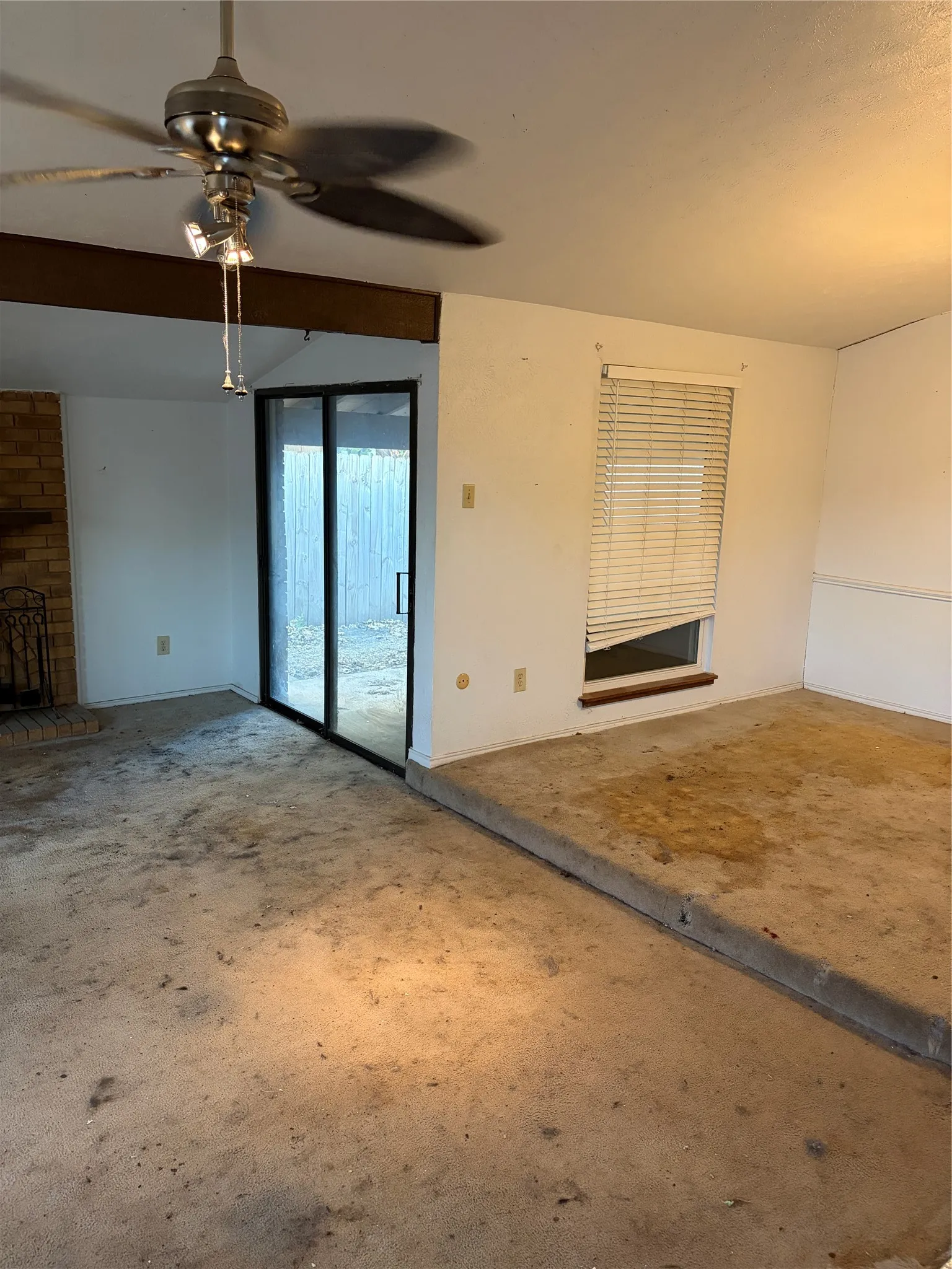 Interior space featuring a brick fireplace, sliding glass door, recessed ceiling fan with integrated lighting, and multi-level flooring