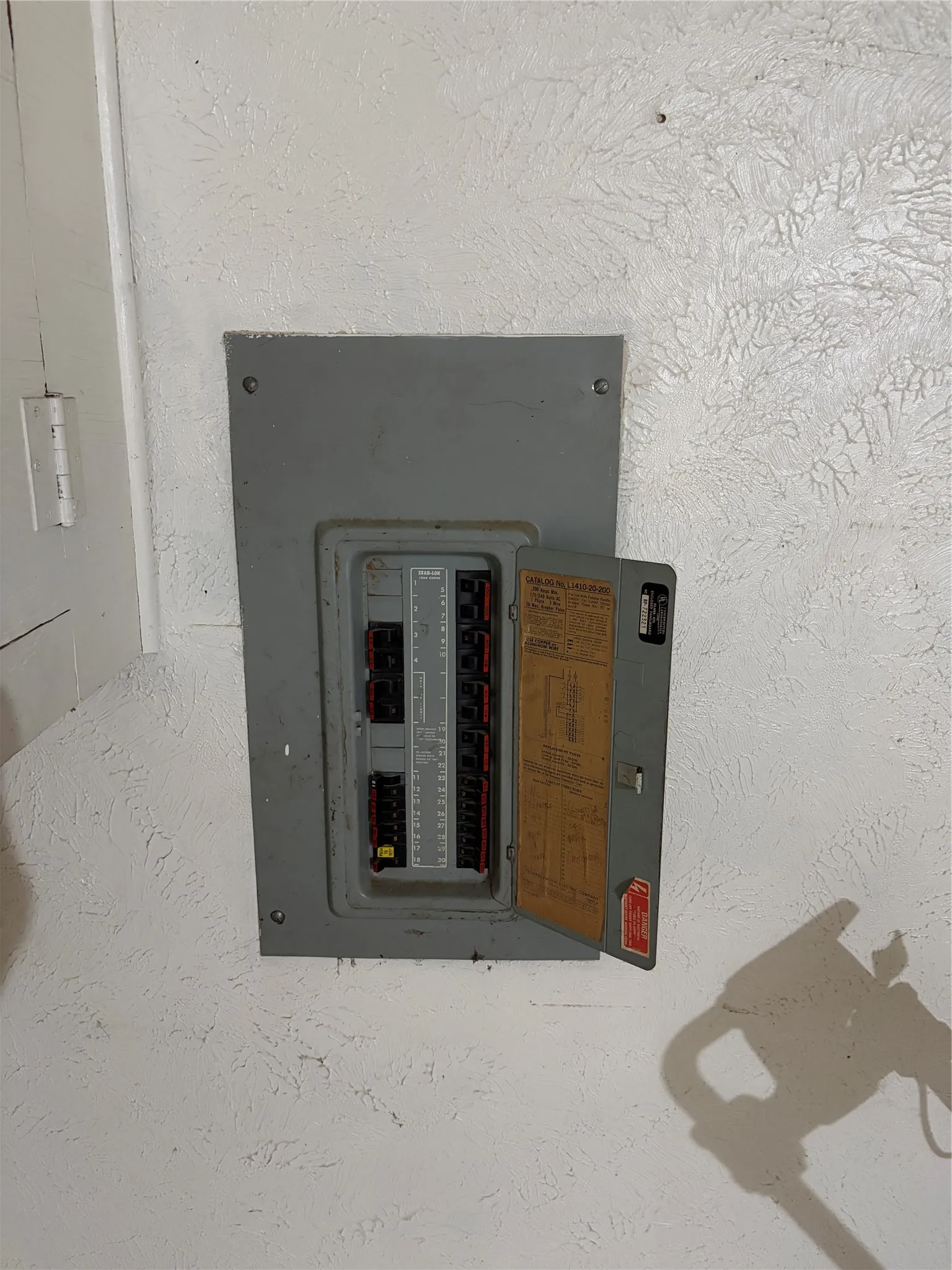 Wall-mounted grey electrical service panel with a hinged access door
