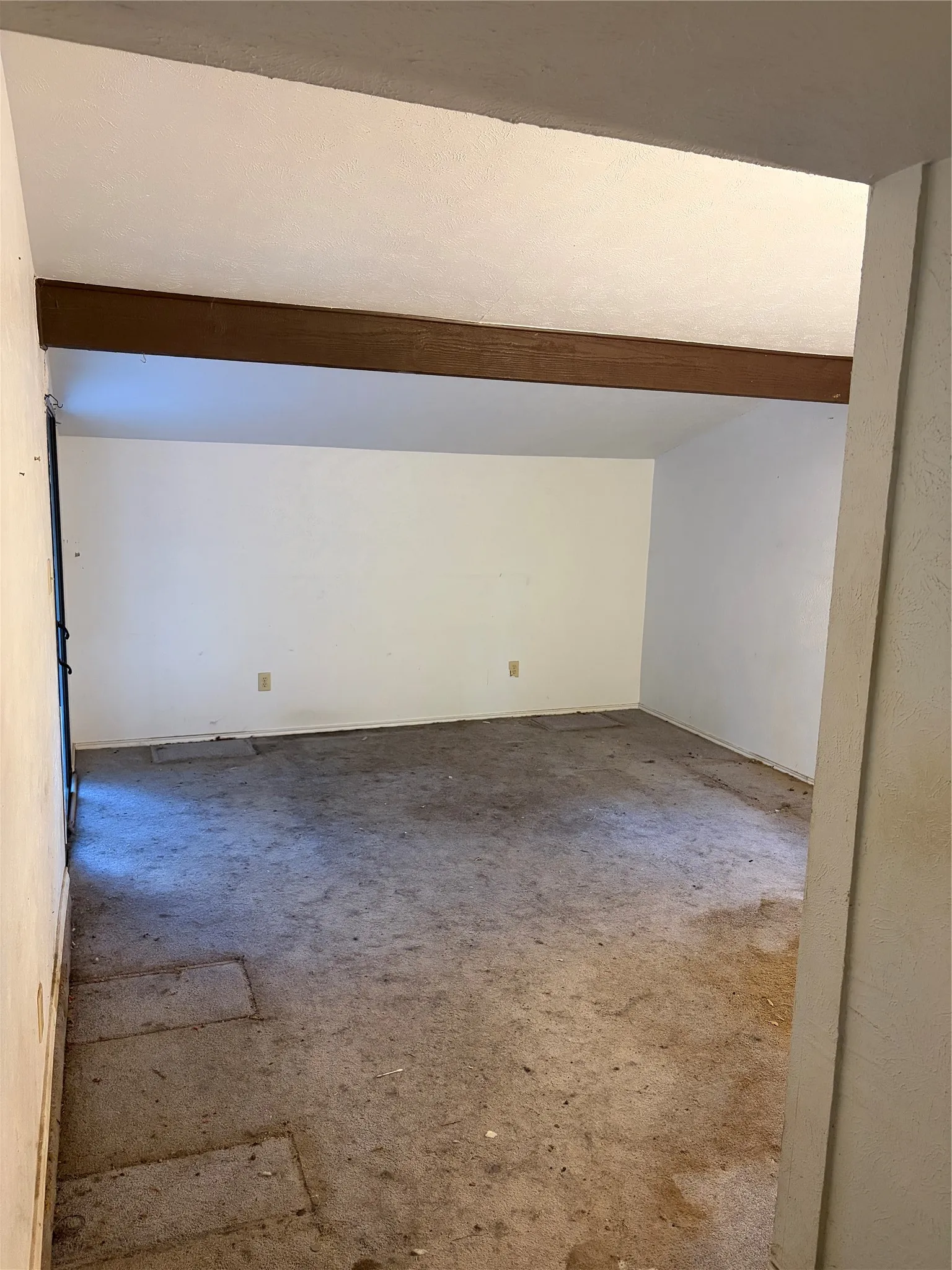 Interior space featuring a vaulted ceiling with an exposed decorative wood beam and wall-to-wall carpeting