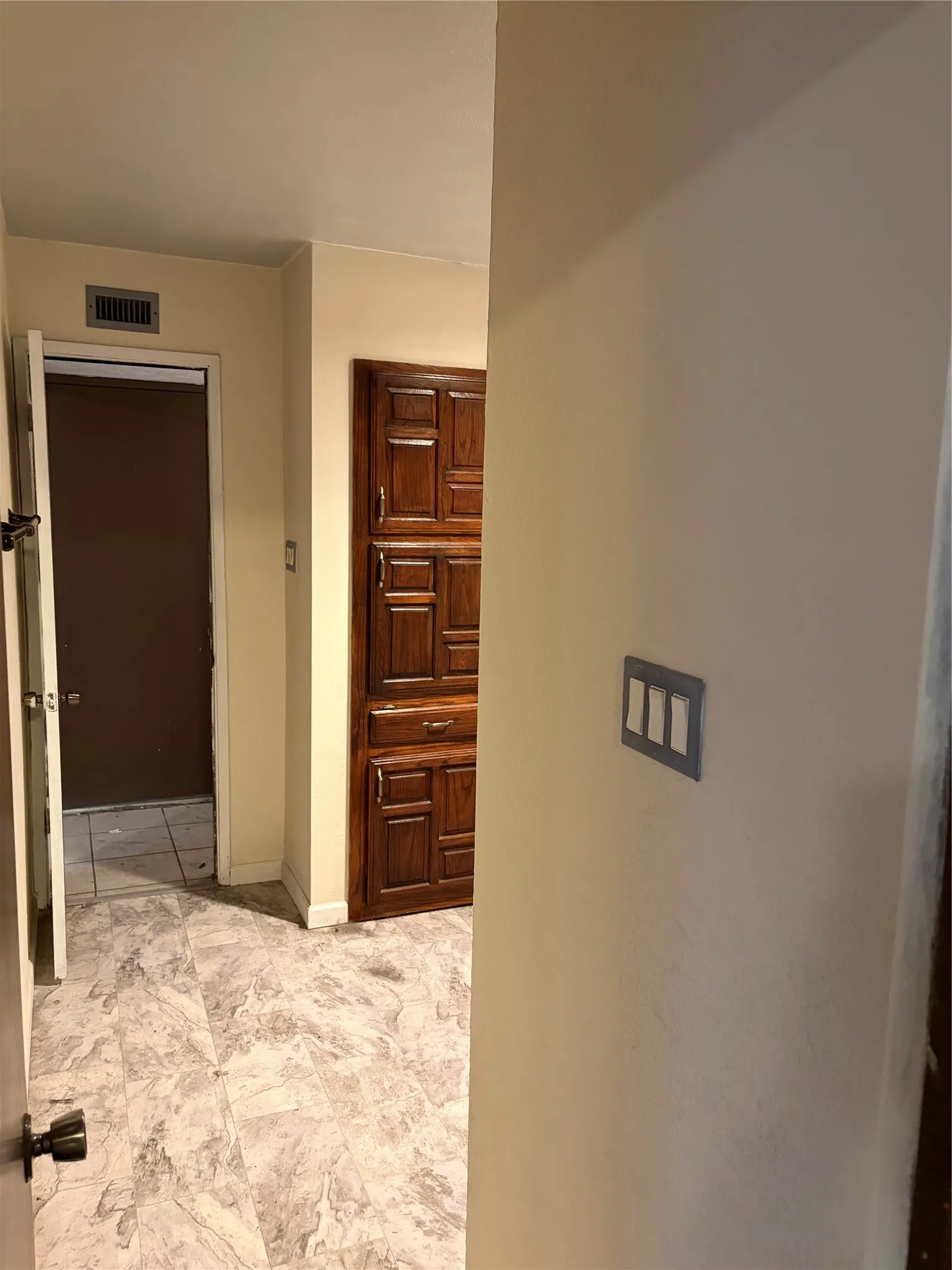 Built-in floor-to-ceiling wood cabinetry, stone-finish tile flooring, and multi-toggle wall switch plates