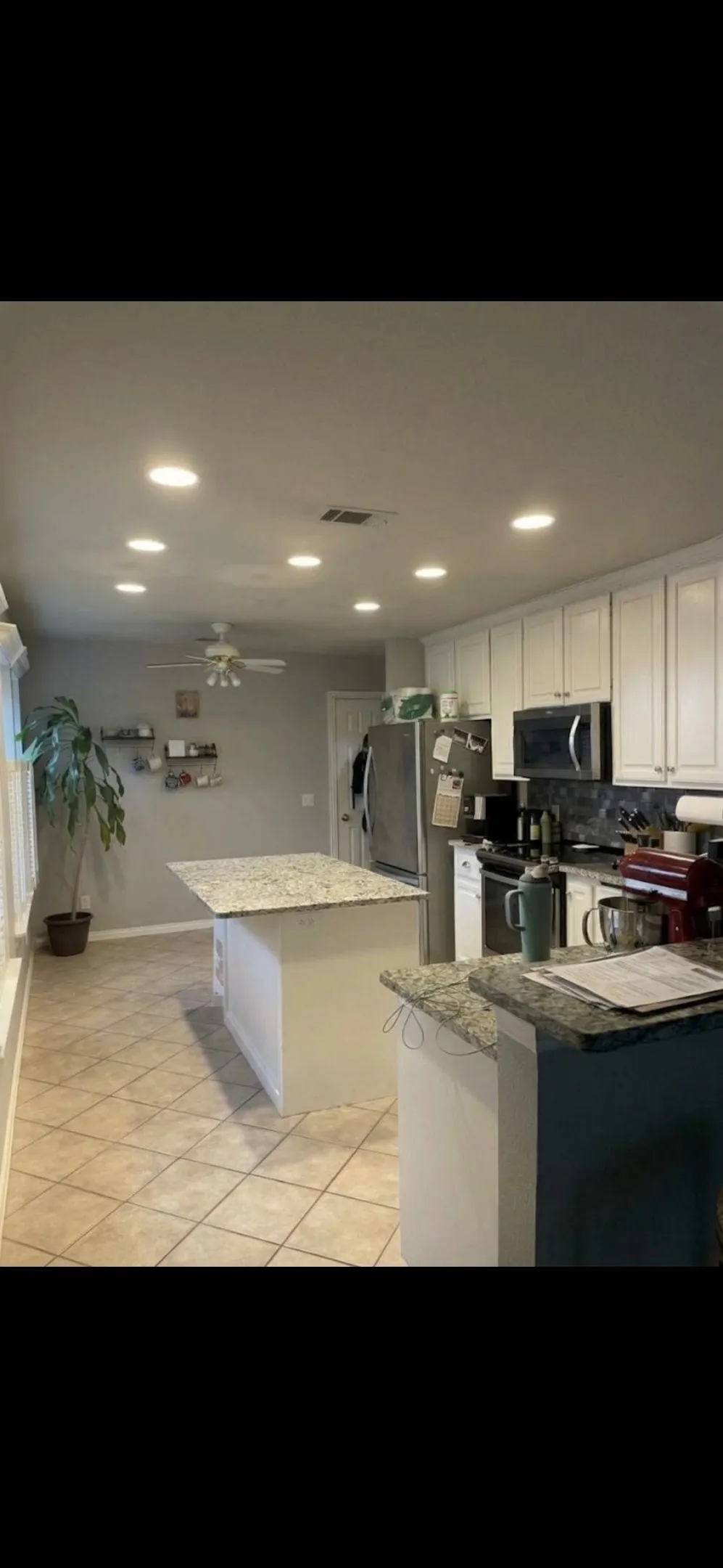 Kitchen featuring white shaker-style cabinetry, stone-surface countertops, central island, tiled flooring, and recessed ceiling lighting