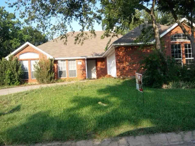 Single-story brick exterior featuring a multi-gabled roofline, arched window detailing, and a concrete driveway