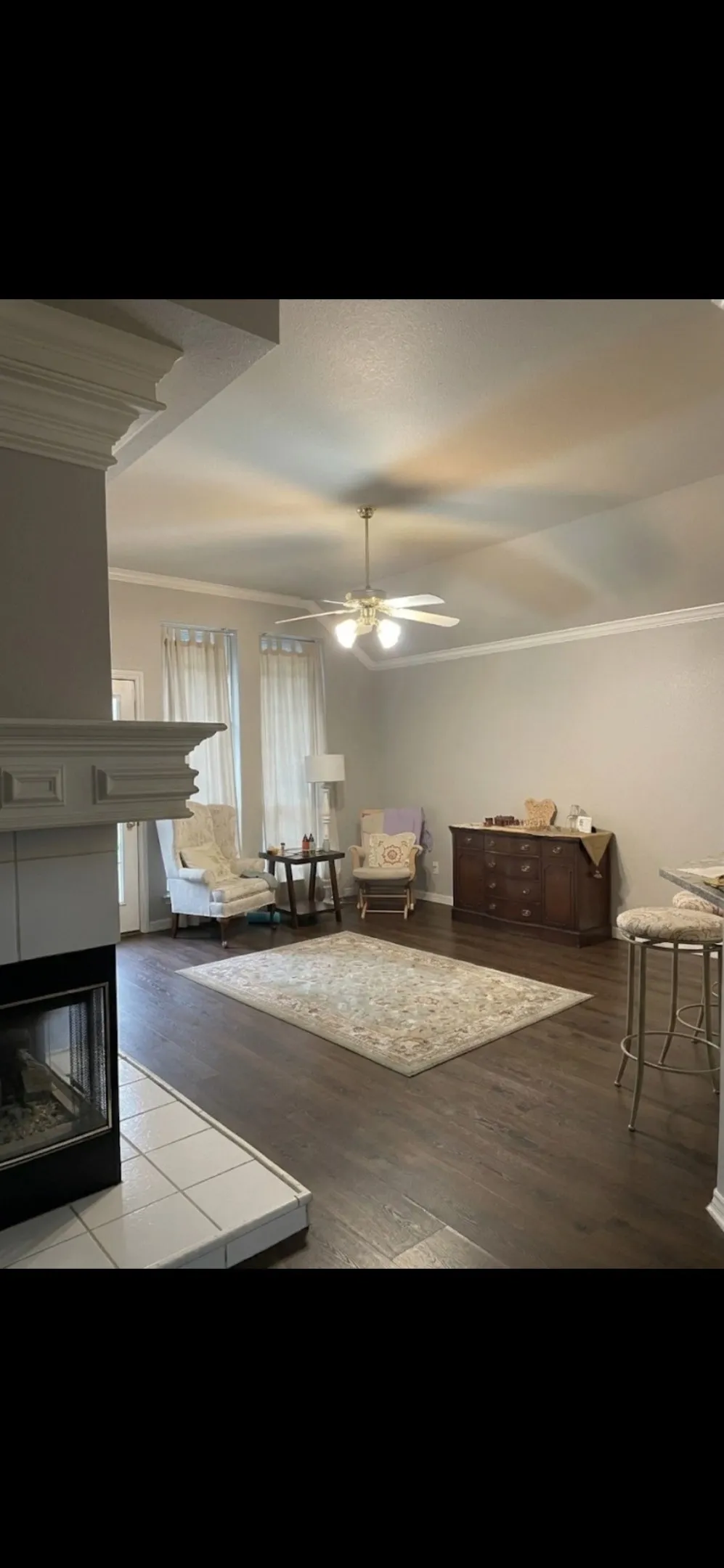 Fireplace with white mantle and tile hearth, vaulted ceilings, crown molding, and wood-finish flooring