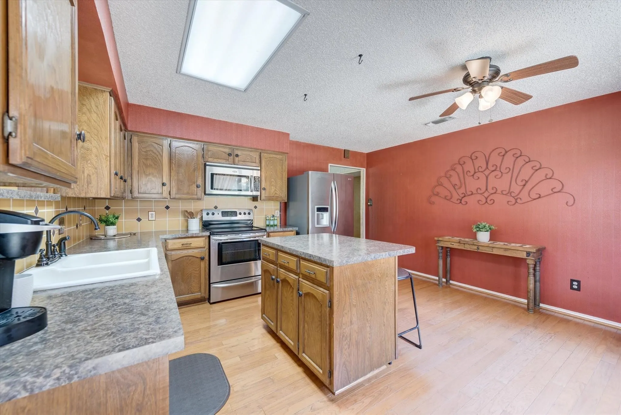 Kitchen featuring wood cabinetry, central island with stone-finish countertop, stainless steel appliances, recessed lighting, and wood-finish flooring