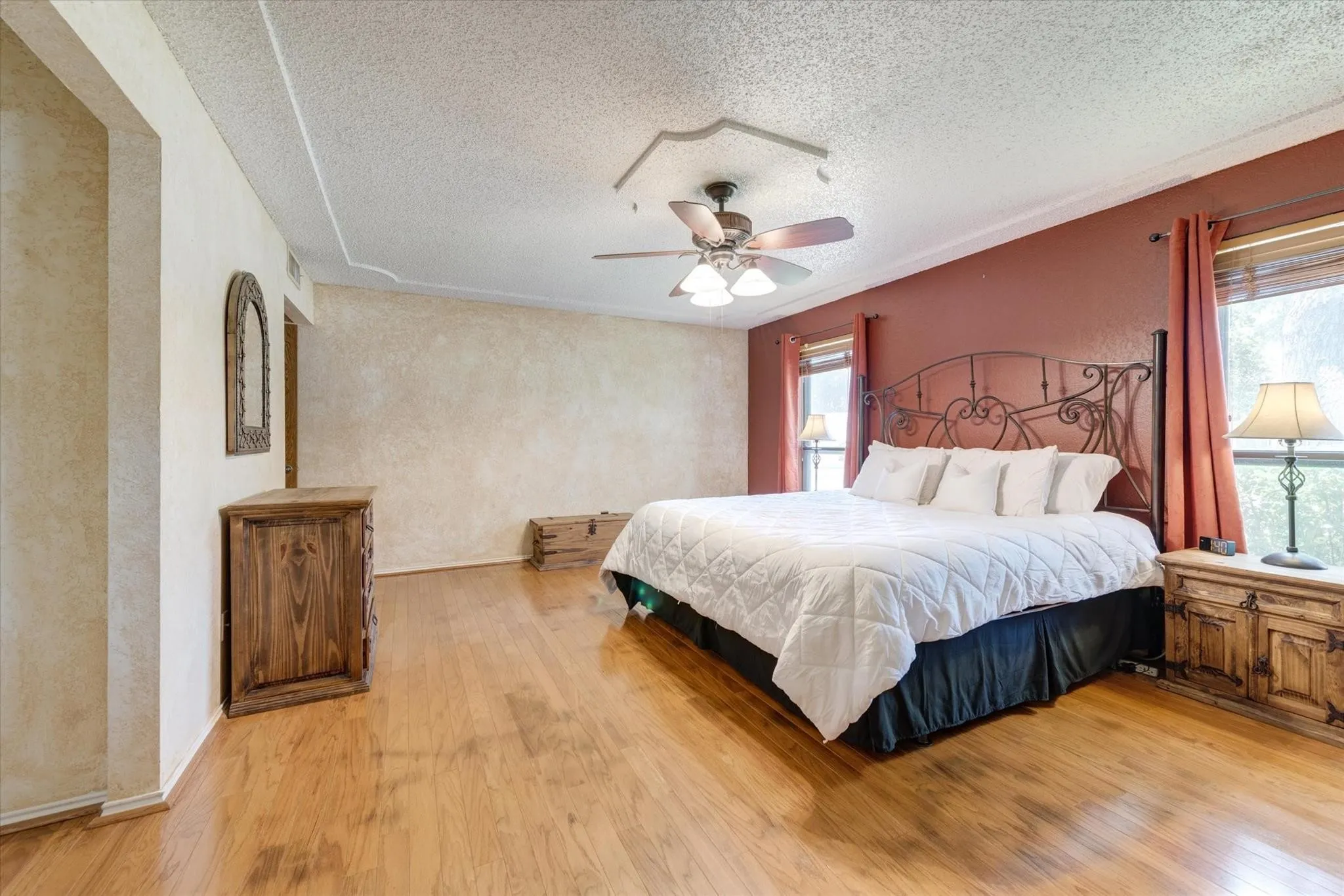 Spacious room featuring wood-finish flooring, a ceiling fan with integrated lighting, and textured wall finishes