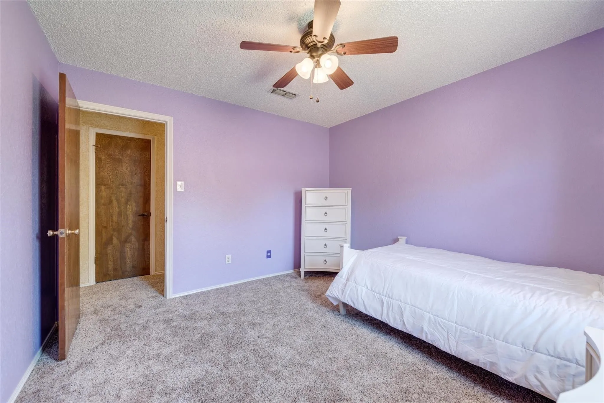 Textured ceiling finish, neutral carpeting, and a multi-blade ceiling fan with integrated lighting fixture