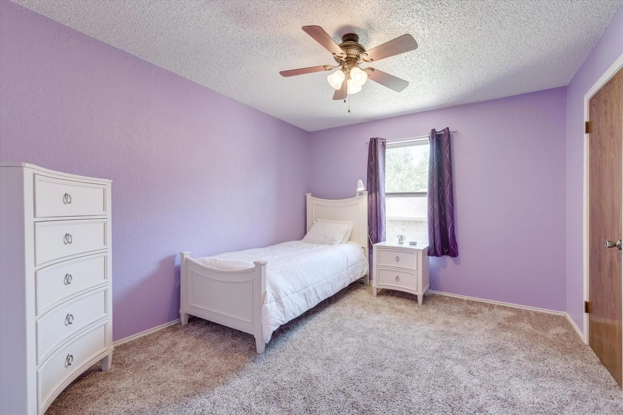 Carpeted flooring, ceiling fan with multi-bulb light fixture, single window, and a wooden interior door