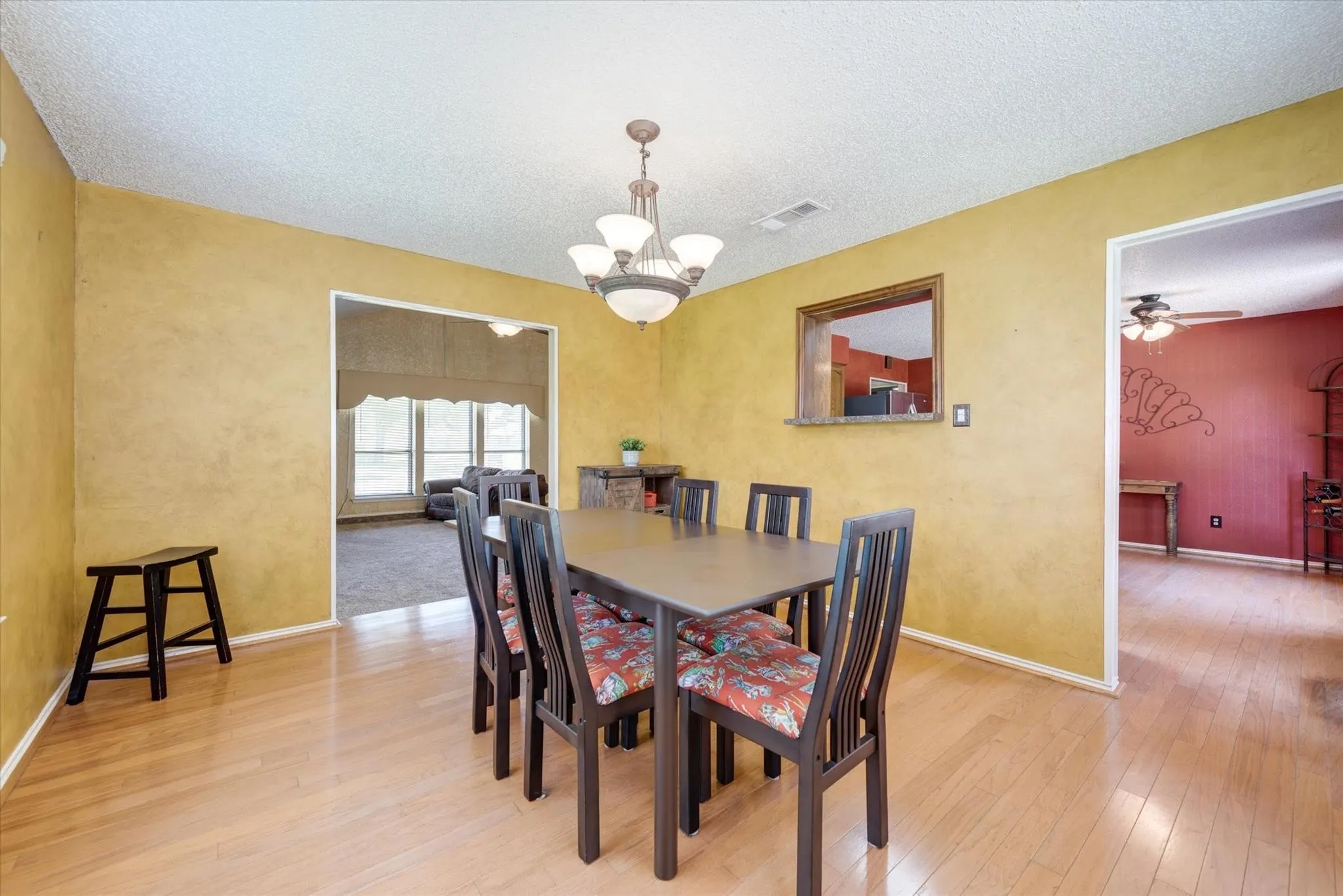 Dining area featuring wood-finish flooring, a multi-arm chandelier, and a wall cutout