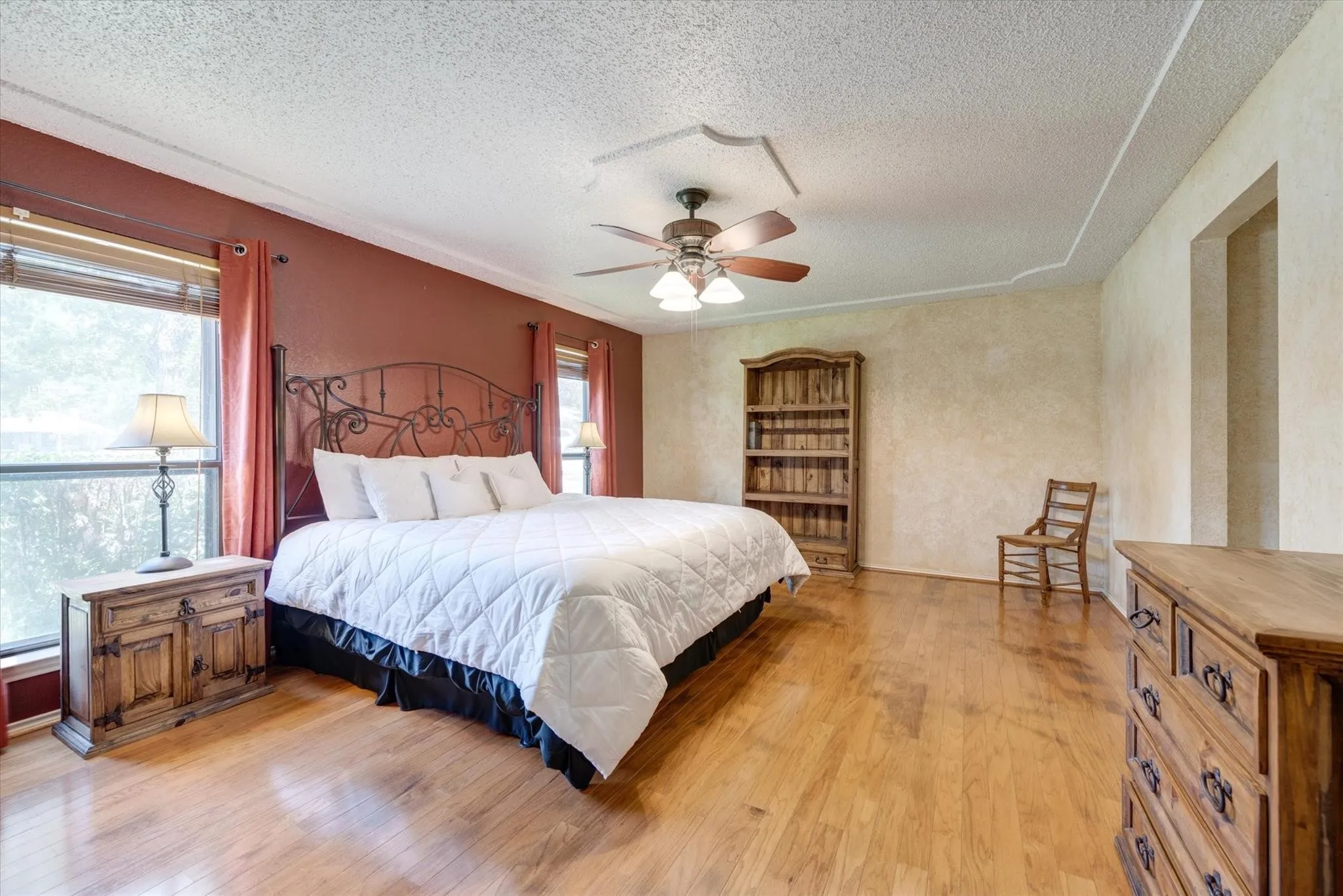Wood-finish flooring, ceiling fan with integrated lighting, textured wall finish, and built-in shelving unit