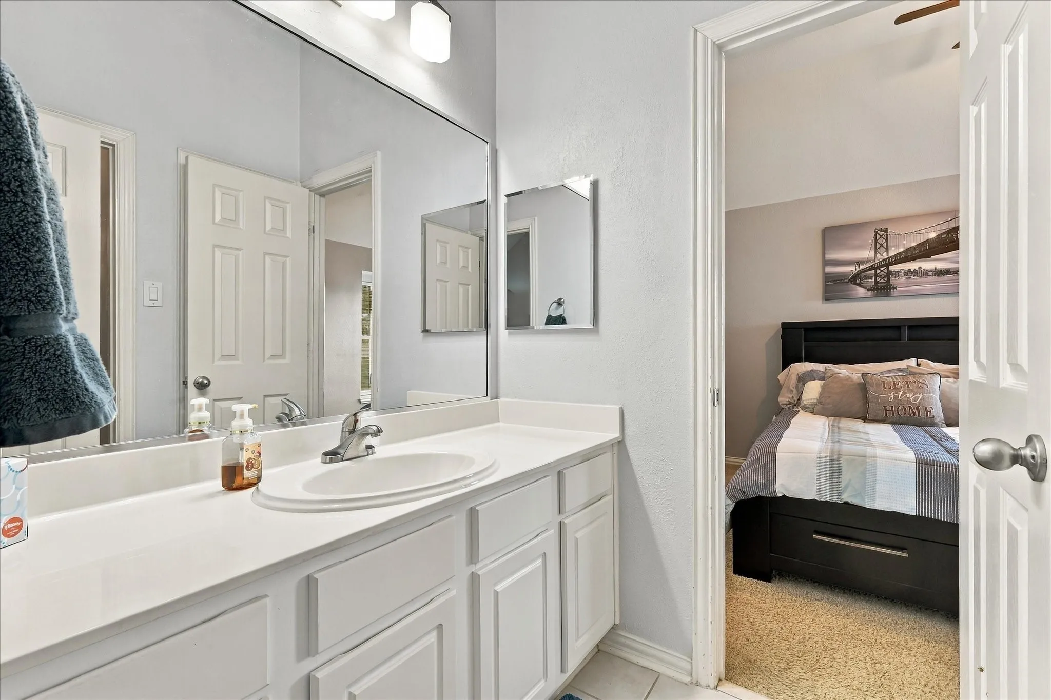 Vanity with a solid-surface countertop, an integrated oval sink, chrome faucet, wall-spanning mirror, and white shaker-style cabinetry