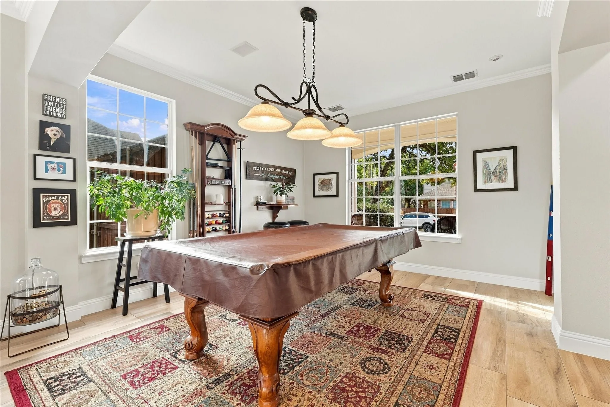 Multi-pane windows, wood-finish flooring, crown molding, and a triple-shade pendant light fixture