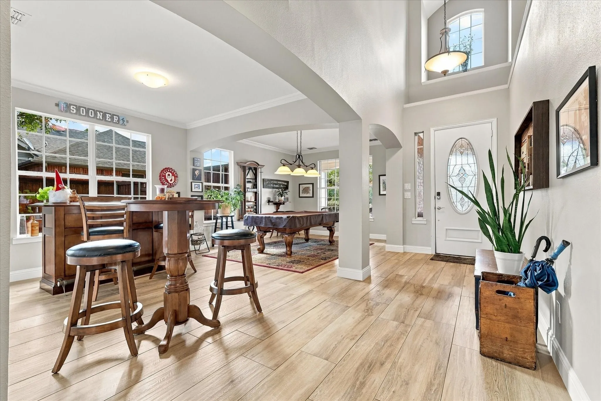 Interior space featuring wood-finish flooring, vaulted ceilings, arched architectural detailing, a multi-pane front door with an oval glass insert, and large-scale windows