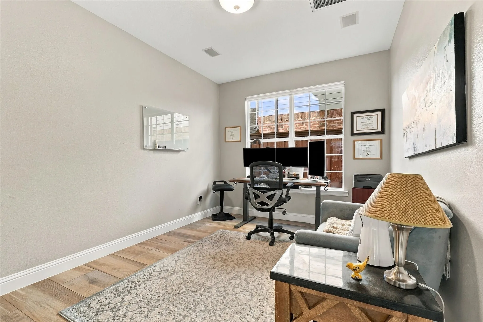 Neutral-toned interior space featuring high ceilings, wood-finish flooring, a multi-pane grid window, and a flush-mount light fixture