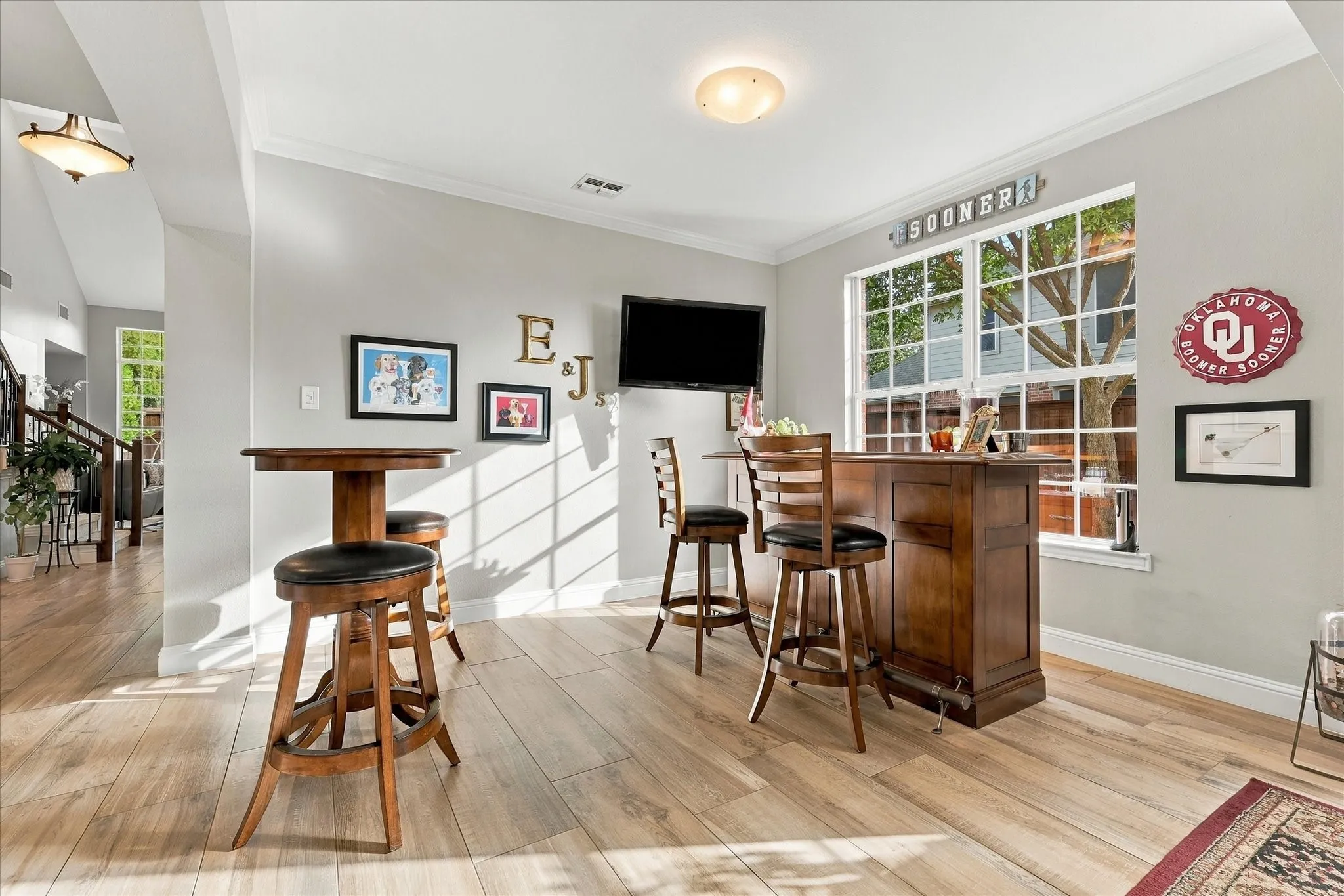 Wood-finish flooring, crown molding, and large grid-pattern windows