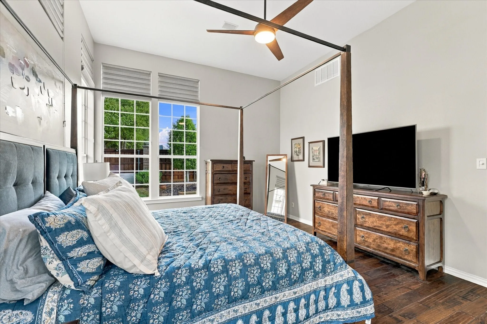 High ceilings featuring a central ceiling fan with integrated lighting, wood-finish flooring, and large windows with integrated blinds