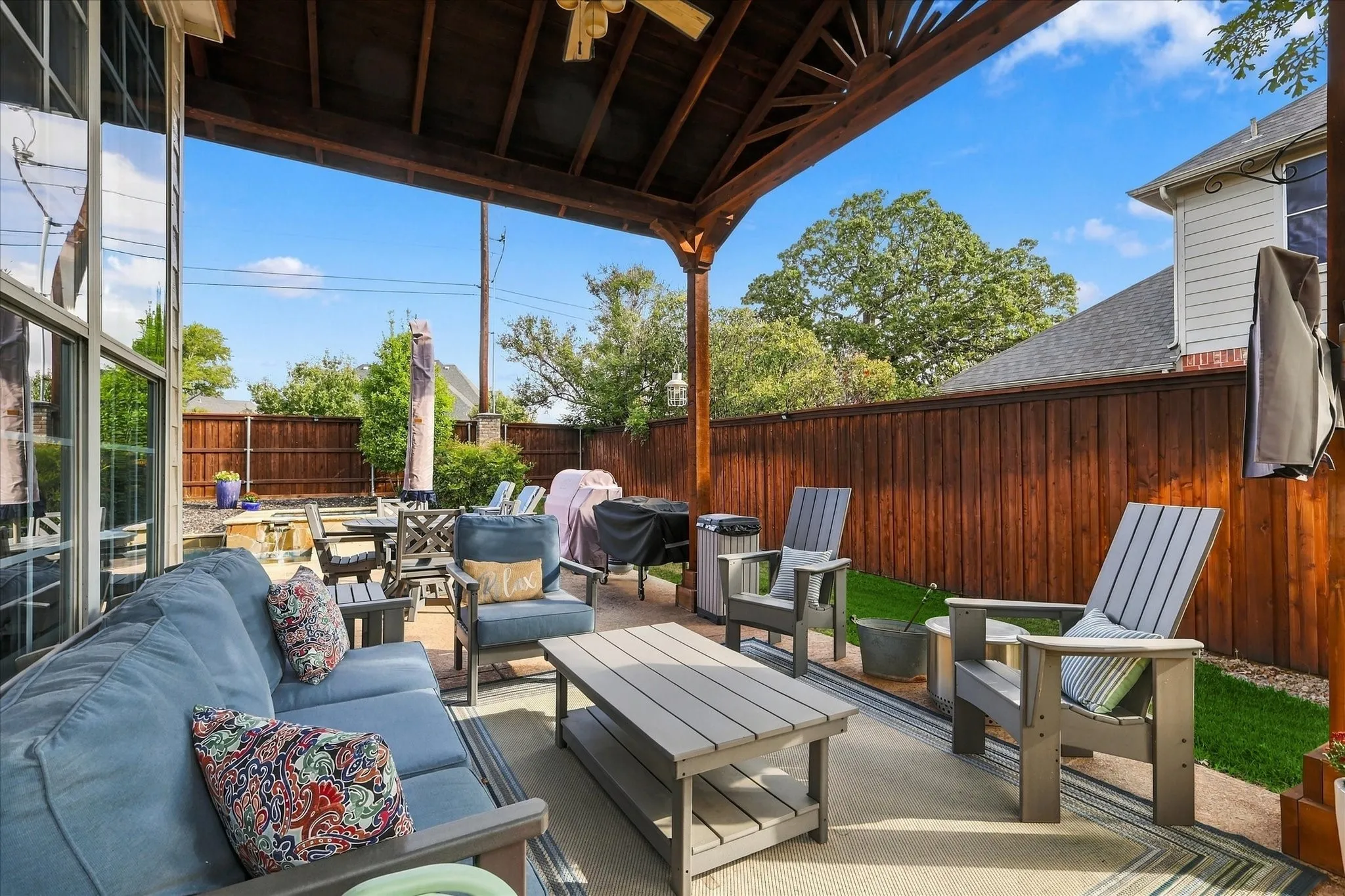 Covered outdoor patio featuring a stained wood pergola, wood-paneled privacy fencing, and concrete hardscaping