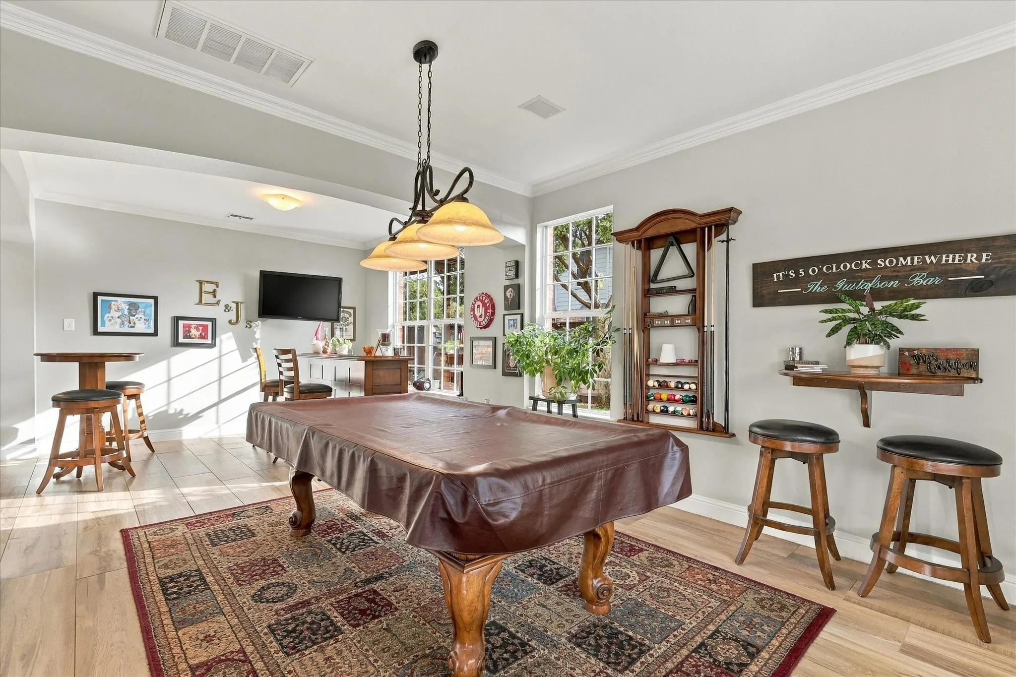 Open-concept area featuring wood-finish flooring, multi-light chandelier with glass shades, tall multi-pane windows, and crown molding