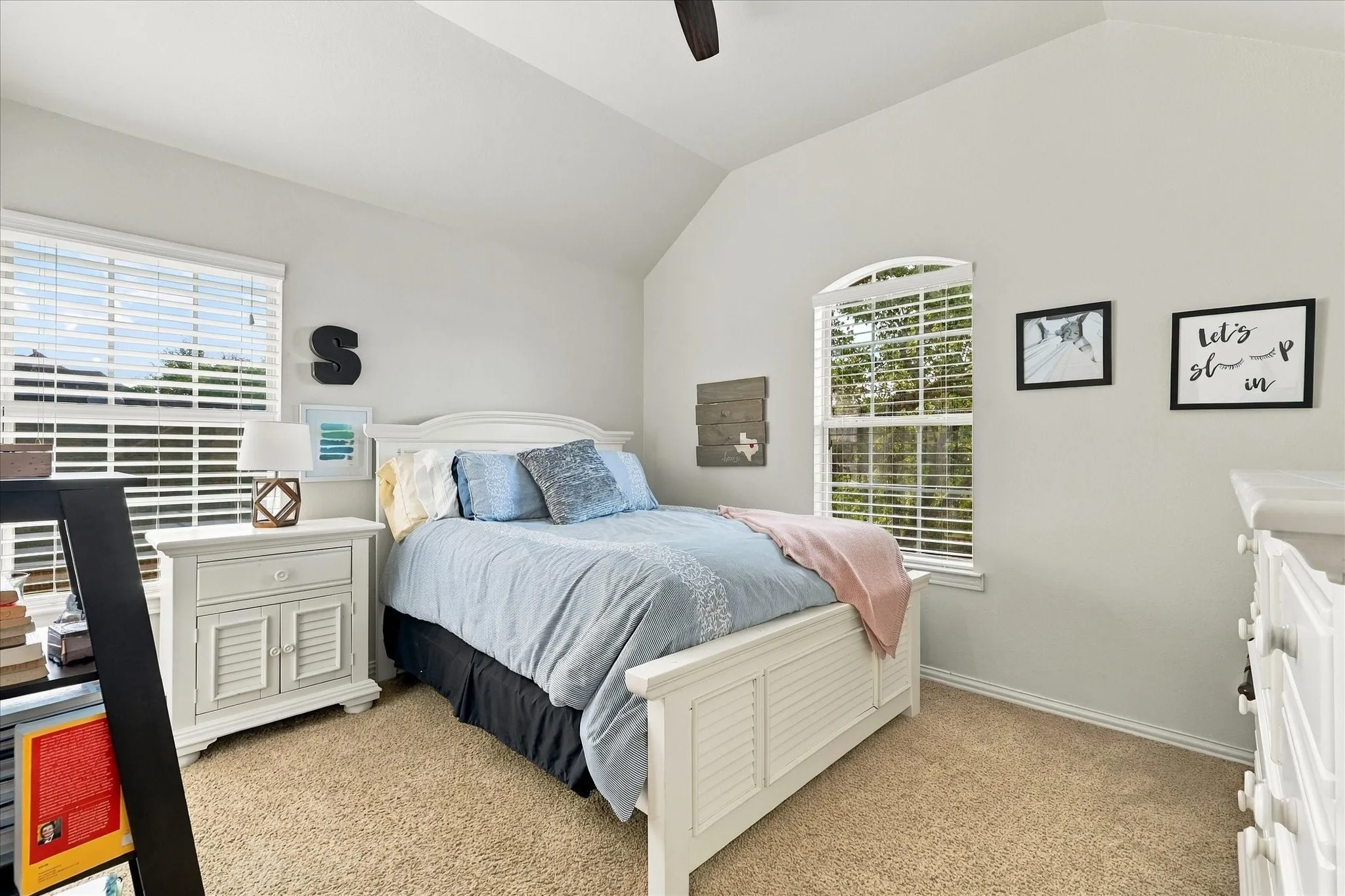 Vaulted ceiling featuring a central light fixture, neutral carpeted flooring, and two windows with arched detailing