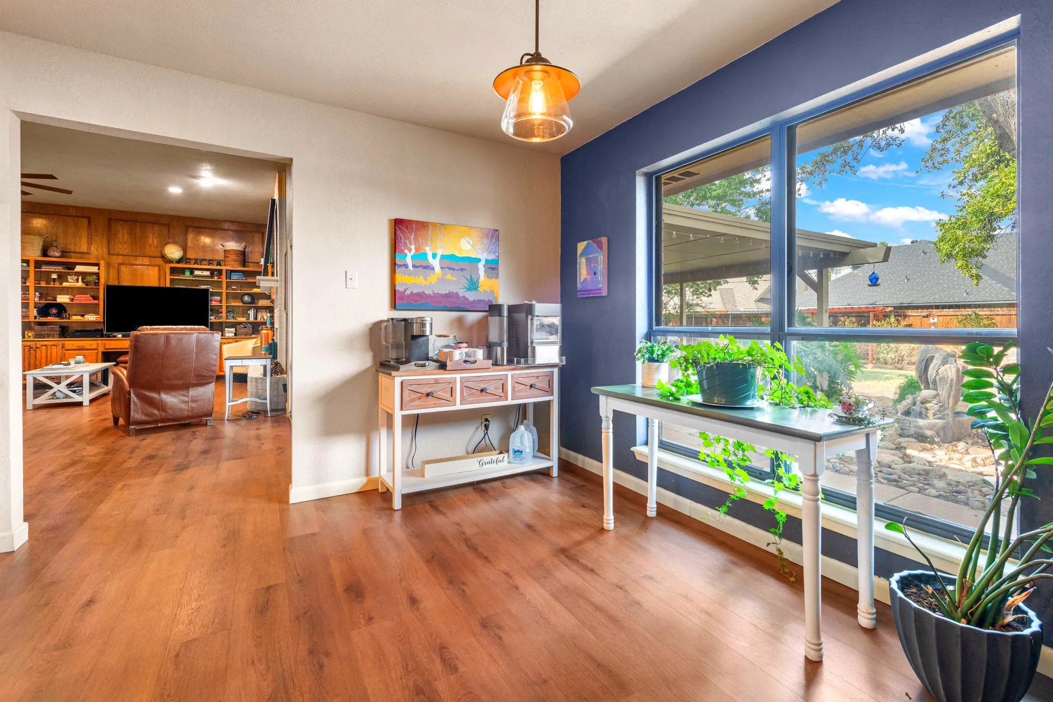 Morning coffee with a view: a bright nook beside a wall of windows overlooking the landscaped backyard and water feature.