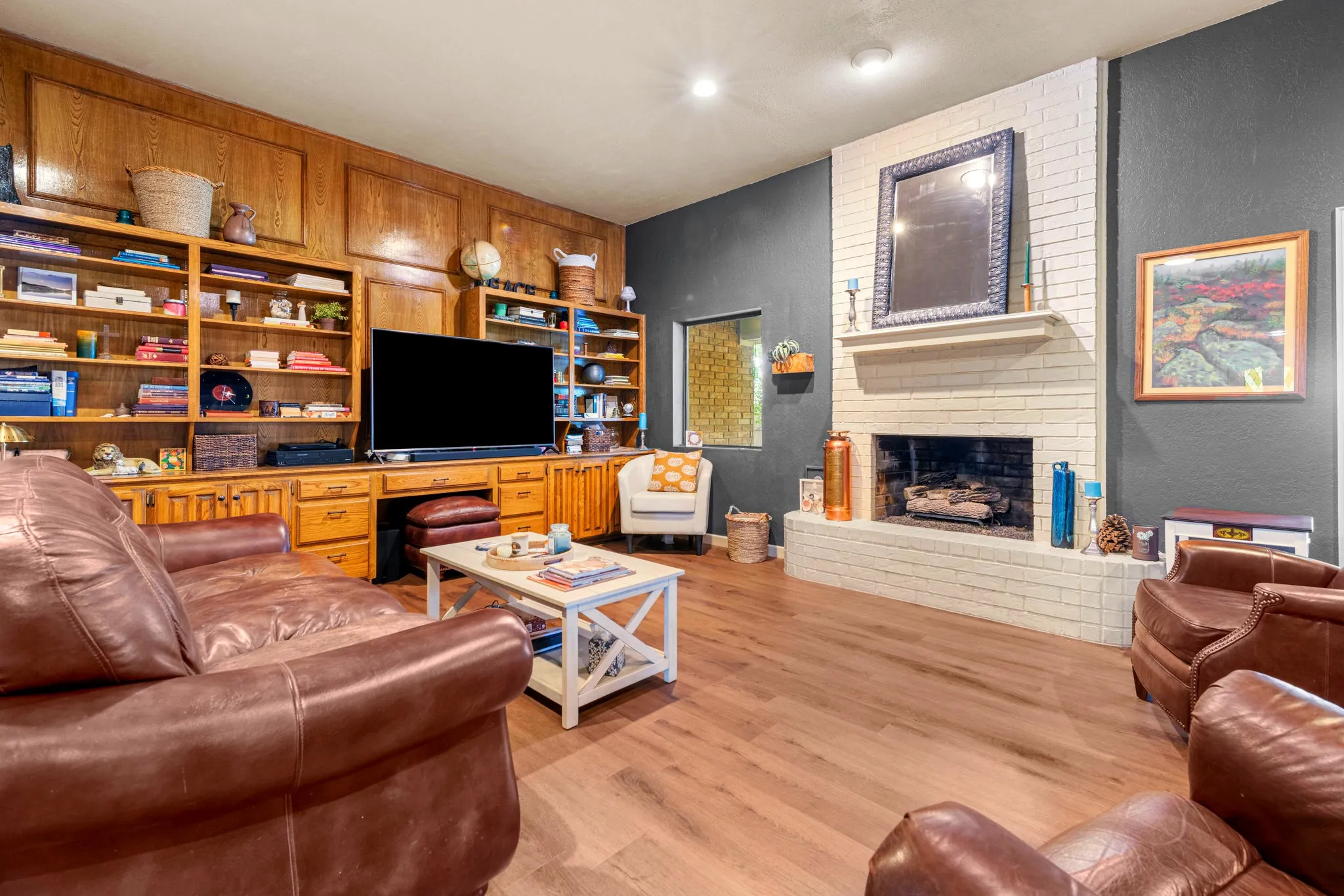 Deep charcoal walls and a crisp white-brick fireplace give the living area a modern, dramatic backdrop.