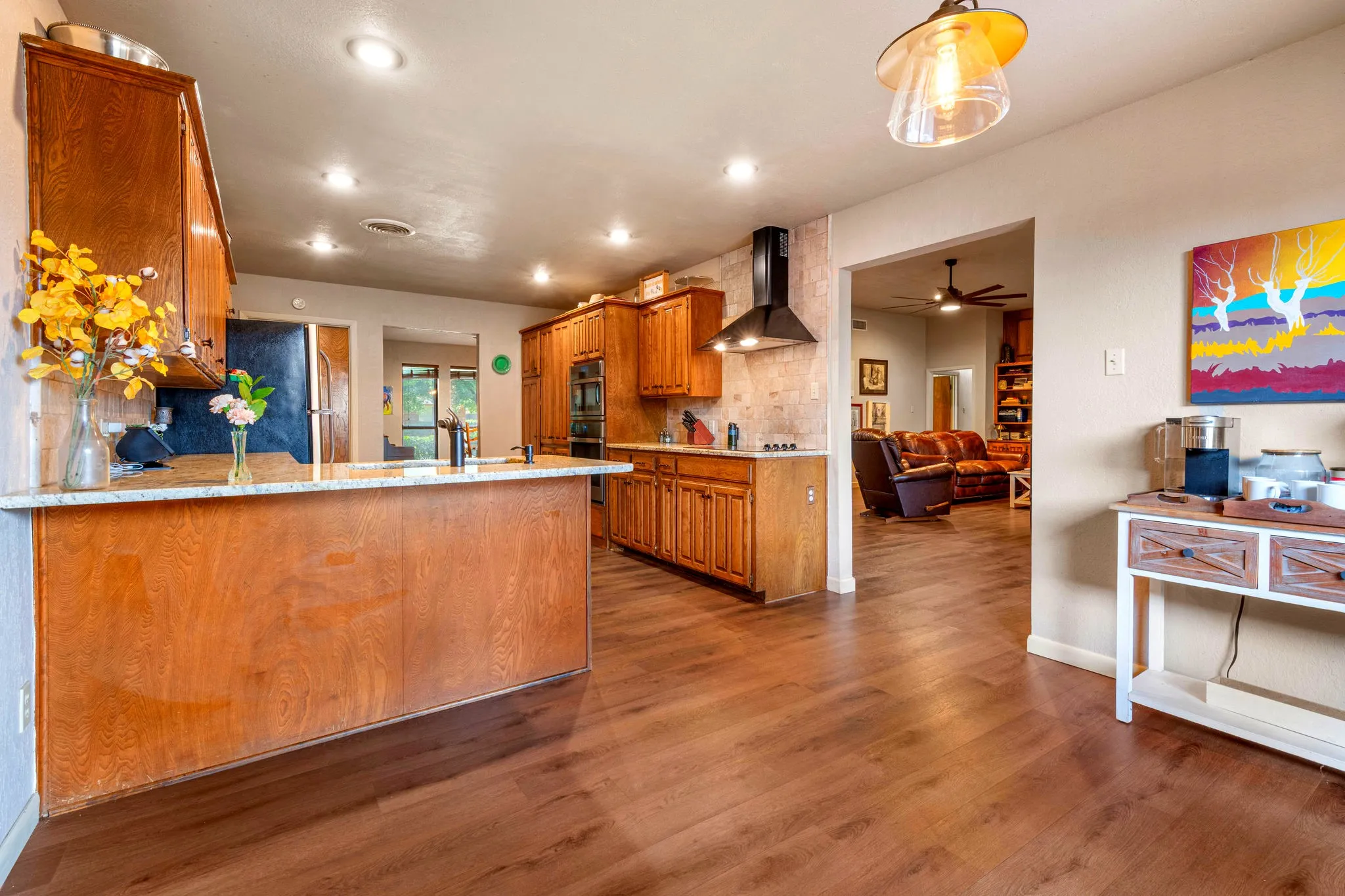 An open kitchen with a granite peninsula and stainless double ovens flows to the living room, ideal for hosting.