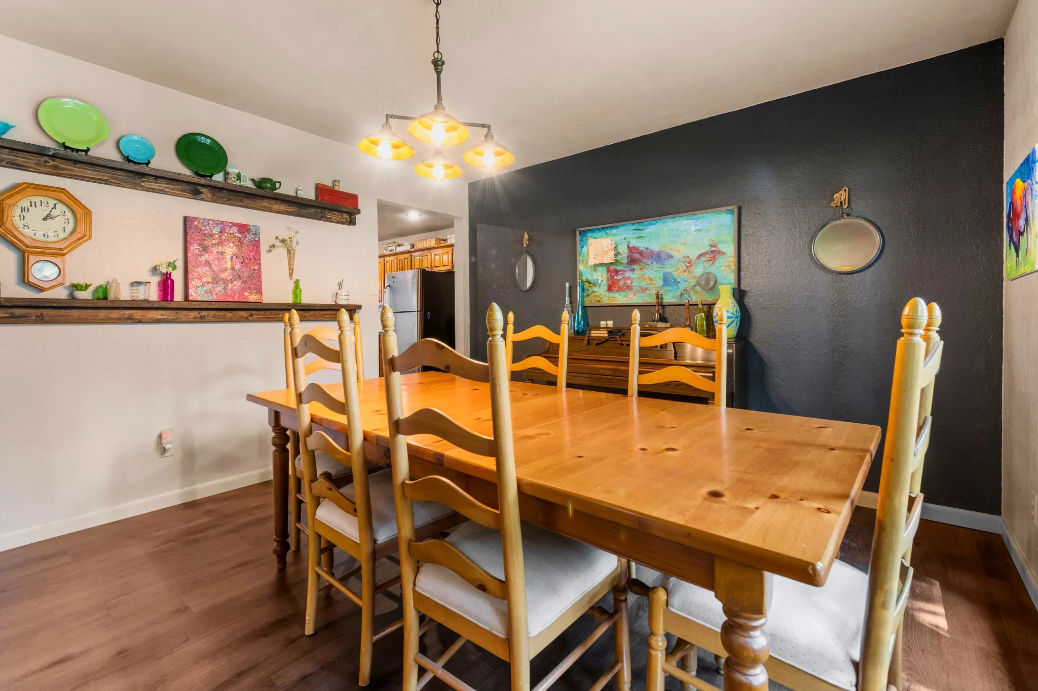 Color, character, and room to gather, with a charcoal accent wall and sunny floating shelves.