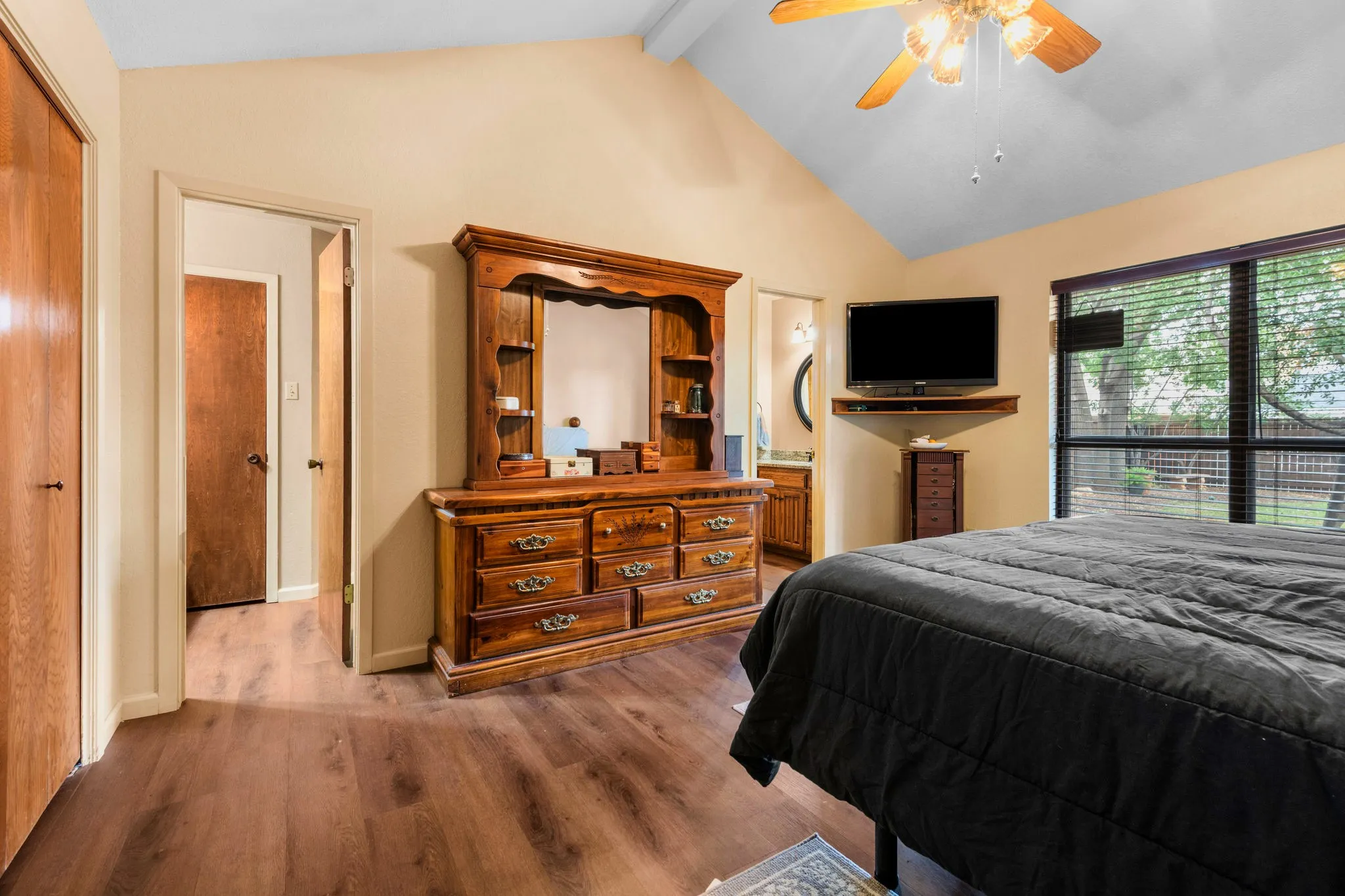 Ceilings rise in graceful angles over this spacious primary bedroom, a honeyed tone haven with roomy storage and a quiet sense of seclusion. A doorway leads to the ensuite bathroom, where private, separate vanities and sinks give each person a space of their own.