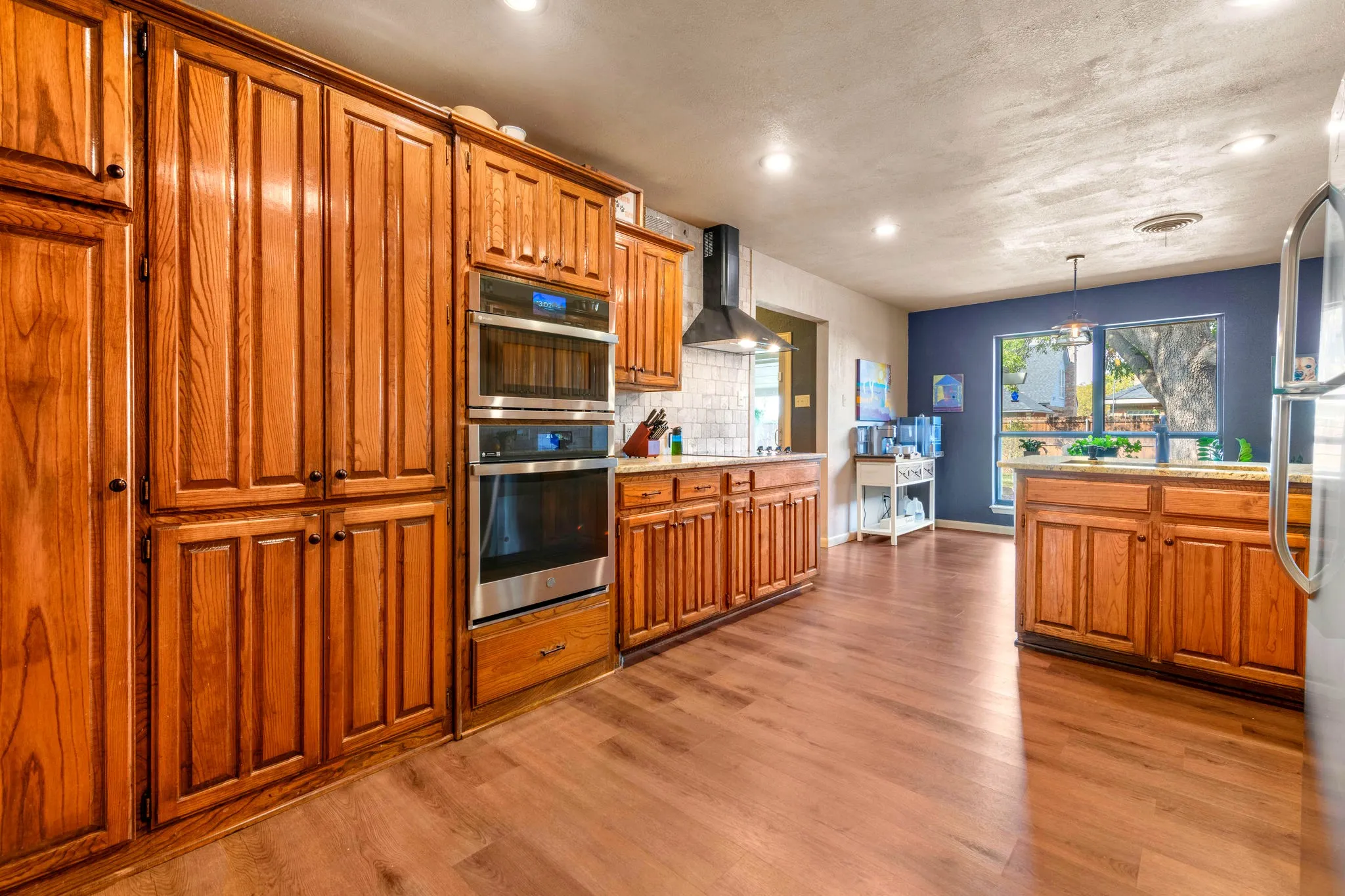A full wall of rich cabinetry, new wall oven and new microwave, and a sleek black range hood offer plenty of storage and serious cooking power.