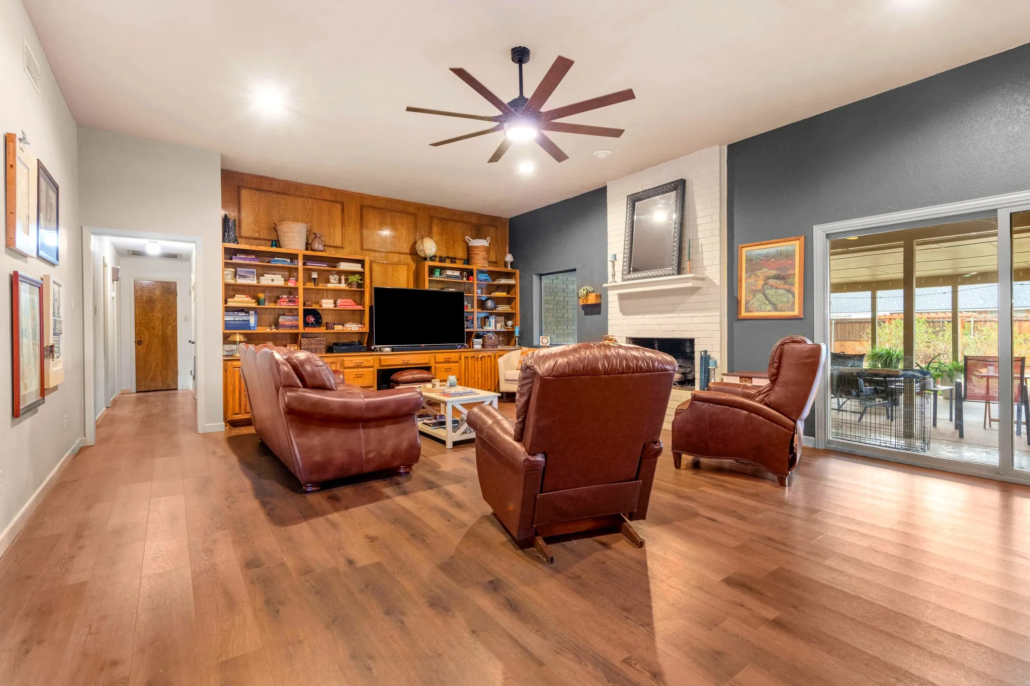 Wood built-ins, a painted-brick fireplace, and sliding glass doors to the covered patio suit cozy nights and easy entertaining.