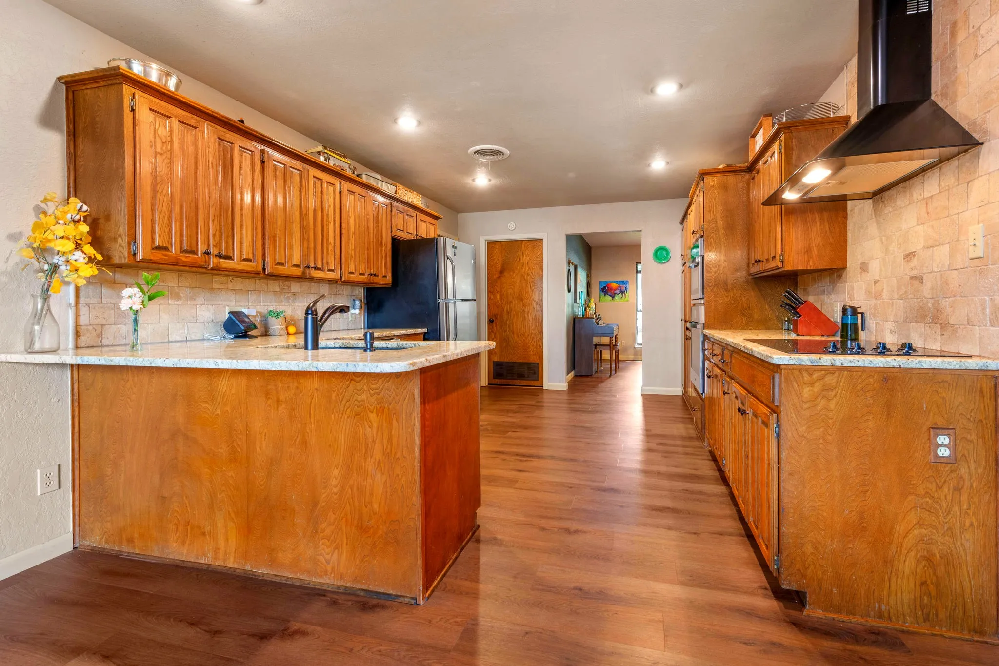 Open, airy sightlines run through the kitchen to the formal dining room, with a dramatic hood vent set against warm stone.