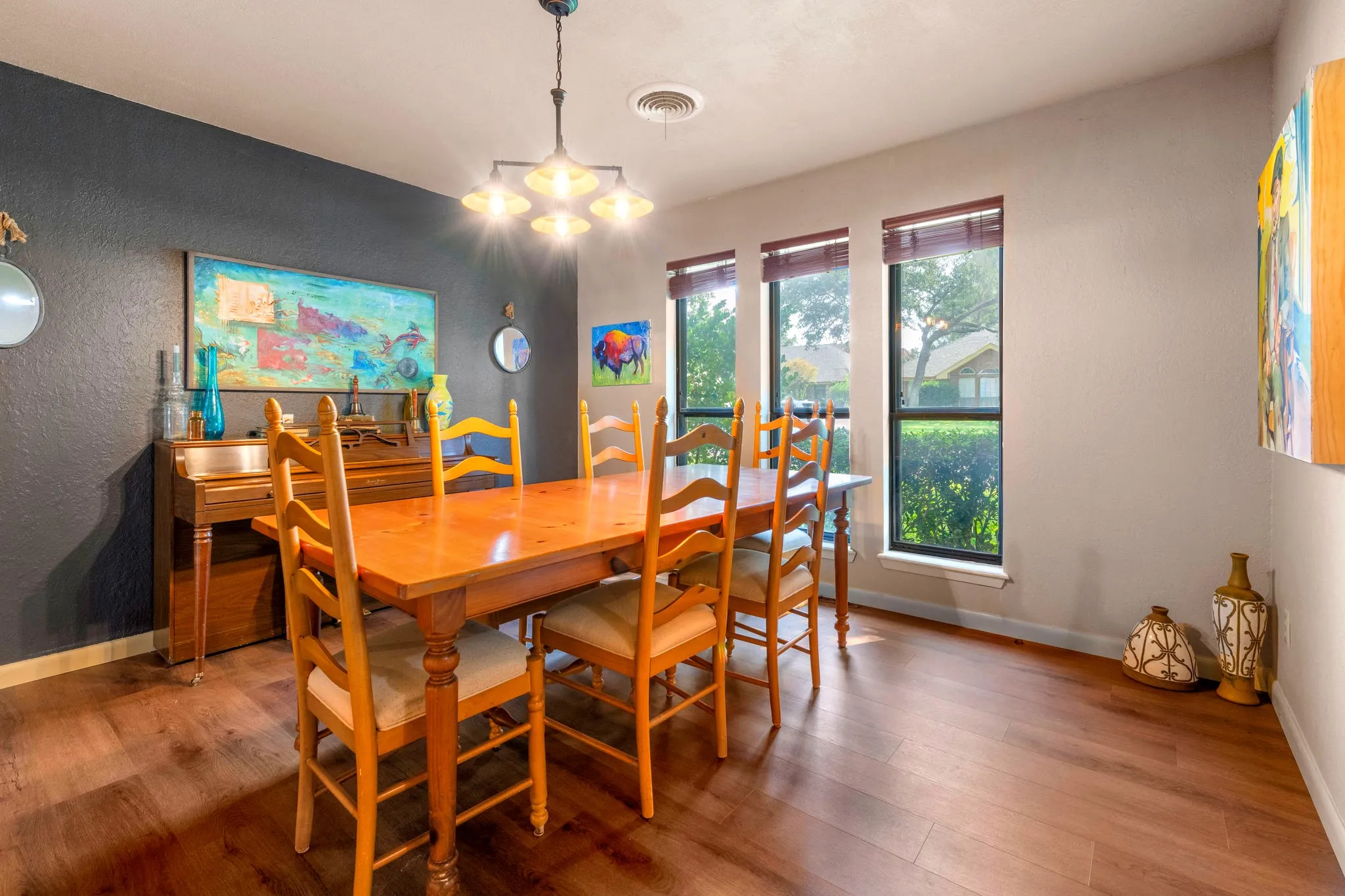 A statement chandelier, and tall windows framing the landscaped front yard make this formal dining room a showpiece.