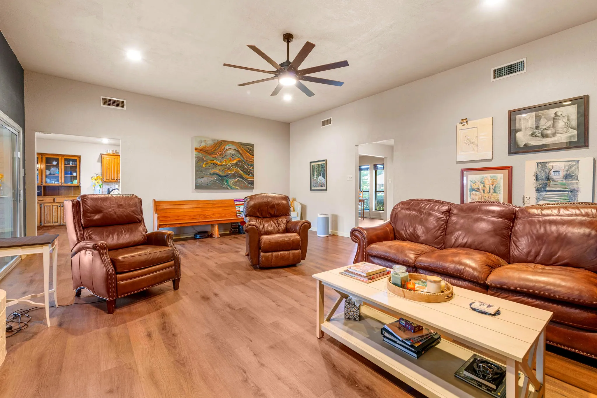 A generous, light-filled living room with a statement ceiling fan, recessed lighting.