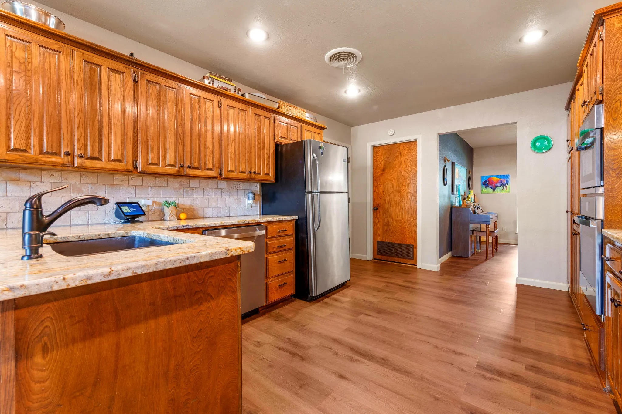 A generous granite counter, pull-down faucet, and warm stone backsplash make everyday cooking a pleasure.