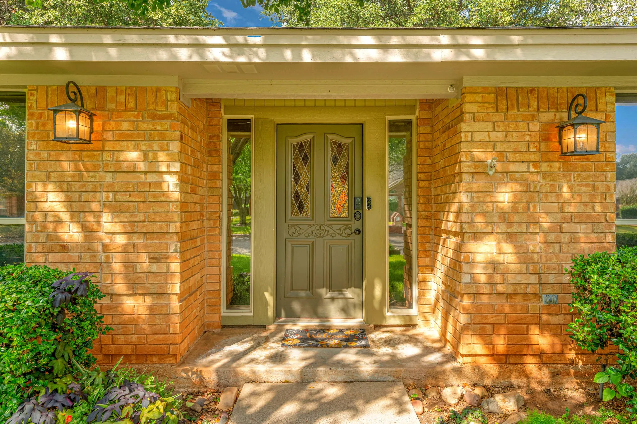 Warm brick, glowing lanterns, and a stained-glass door make the entry feel like a hand-crafted invitation.