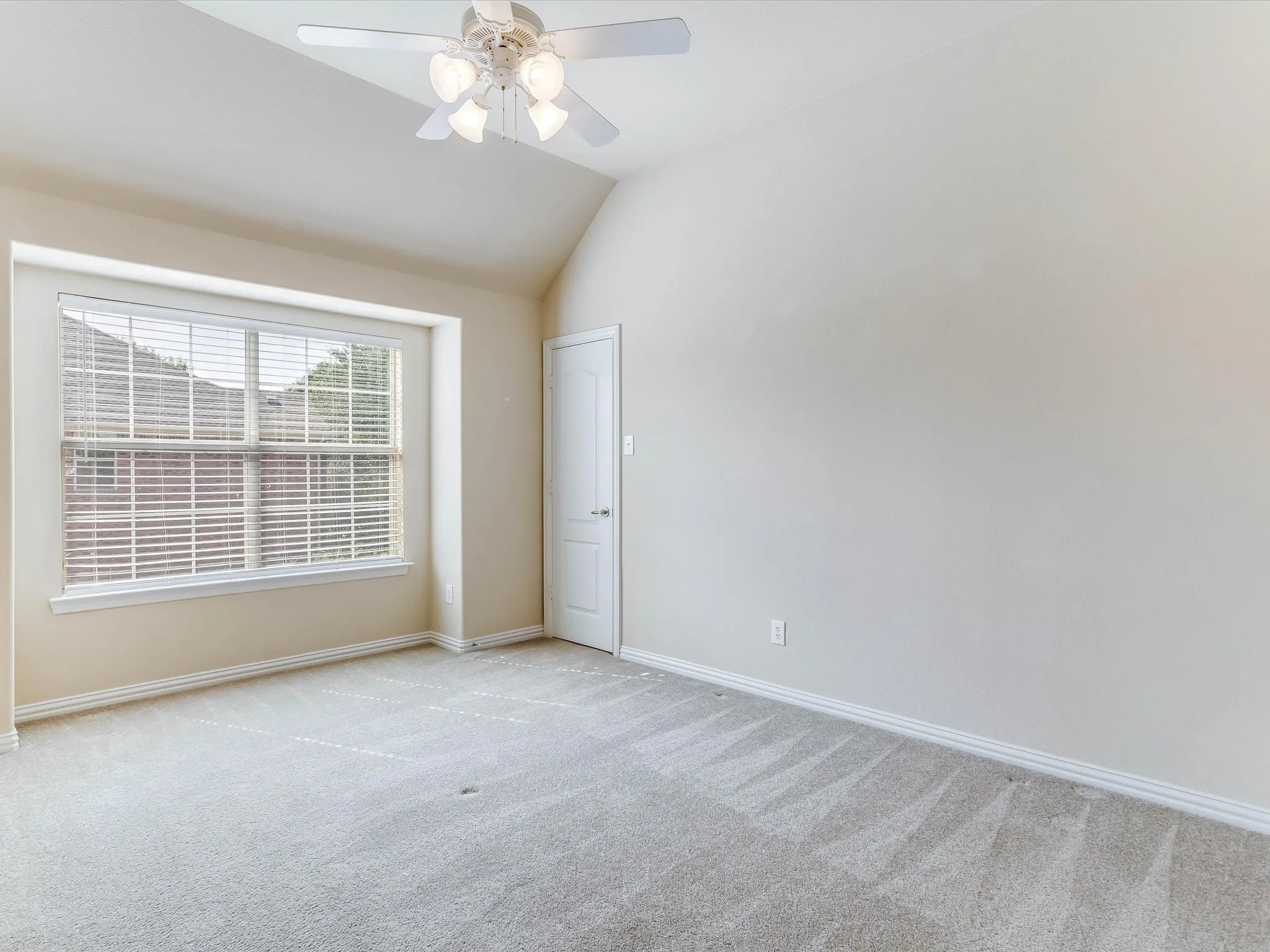 Vaulted ceiling with an attached multi-light ceiling fan, neutral wall tones, window with interior blinds, and wall-to-wall carpeting
