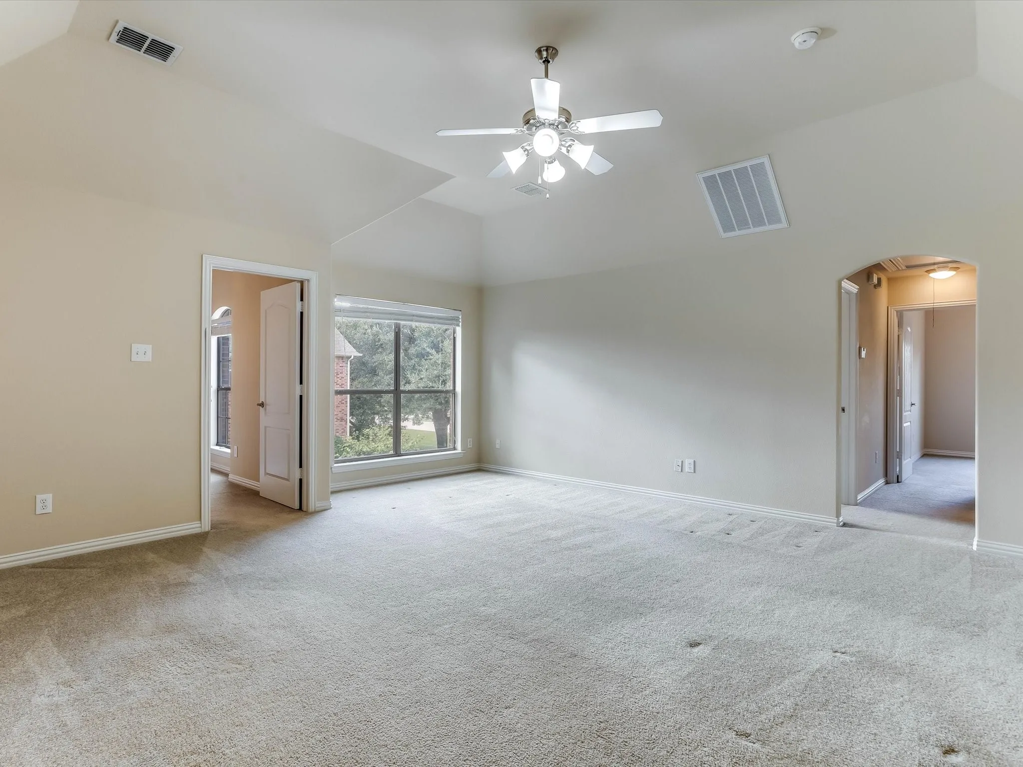 Vaulted ceilings featuring a multi-light ceiling fan, wall-to-wall carpeting, and an arched entryway