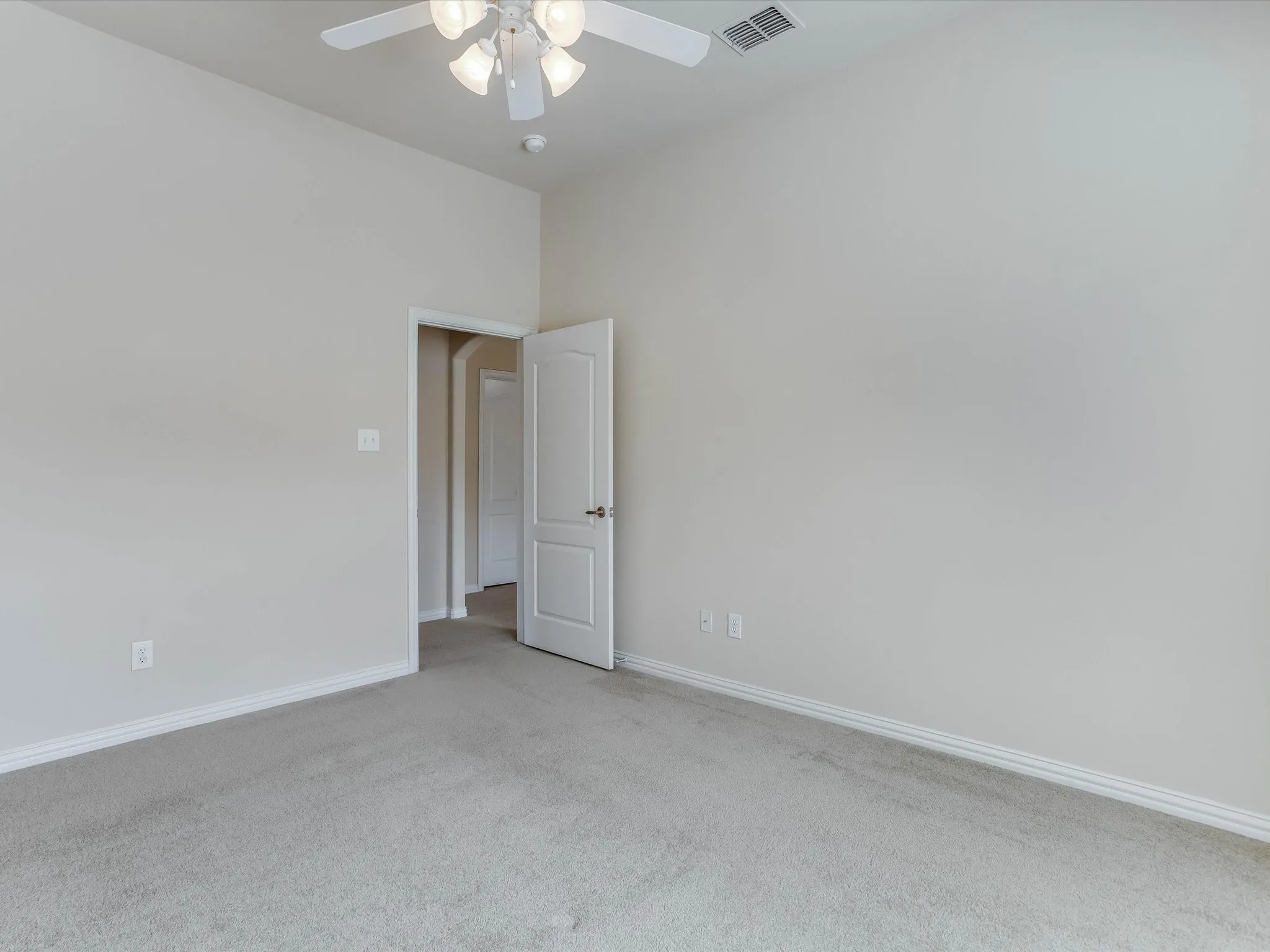 Neutral wall tones paired with neutral carpeting, high ceilings, and an overhead ceiling fan with integrated lighting
